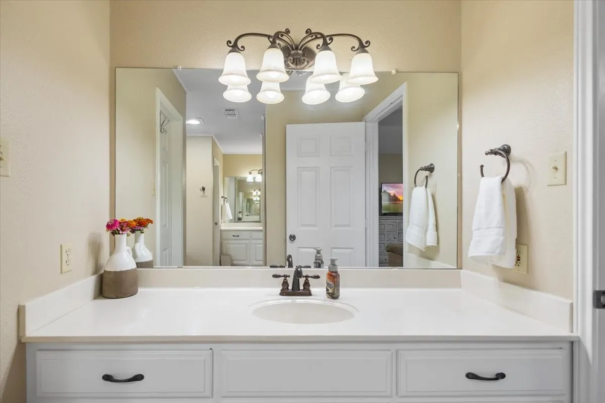 Spacious vanity featuring a white countertop with an integrated sink, dark bronze faucet, and a large mirror