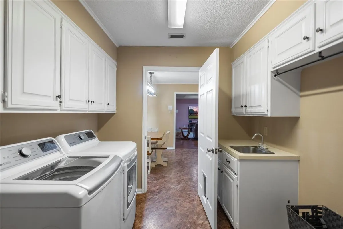 Laundry area featuring white cabinetry, a utility sink with a countertop, and patterned flooring