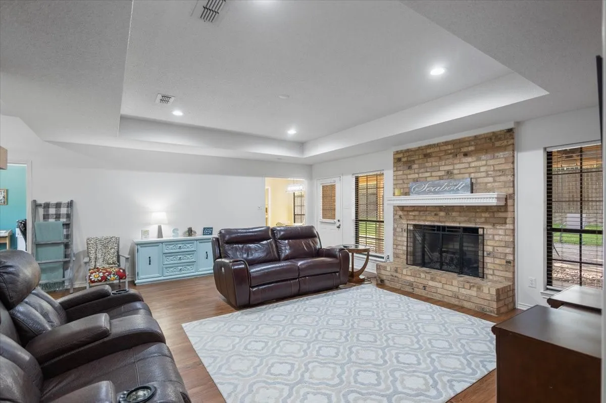 Living area with wood-finish flooring, tray ceiling, and recessed lighting