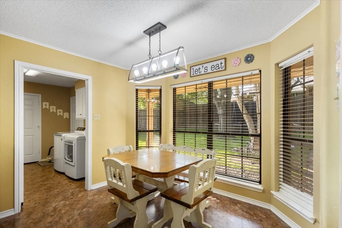 Dining area featuring a bay window with horizontal blinds, a ceiling-mounted light fixture, and wood-finish flooring