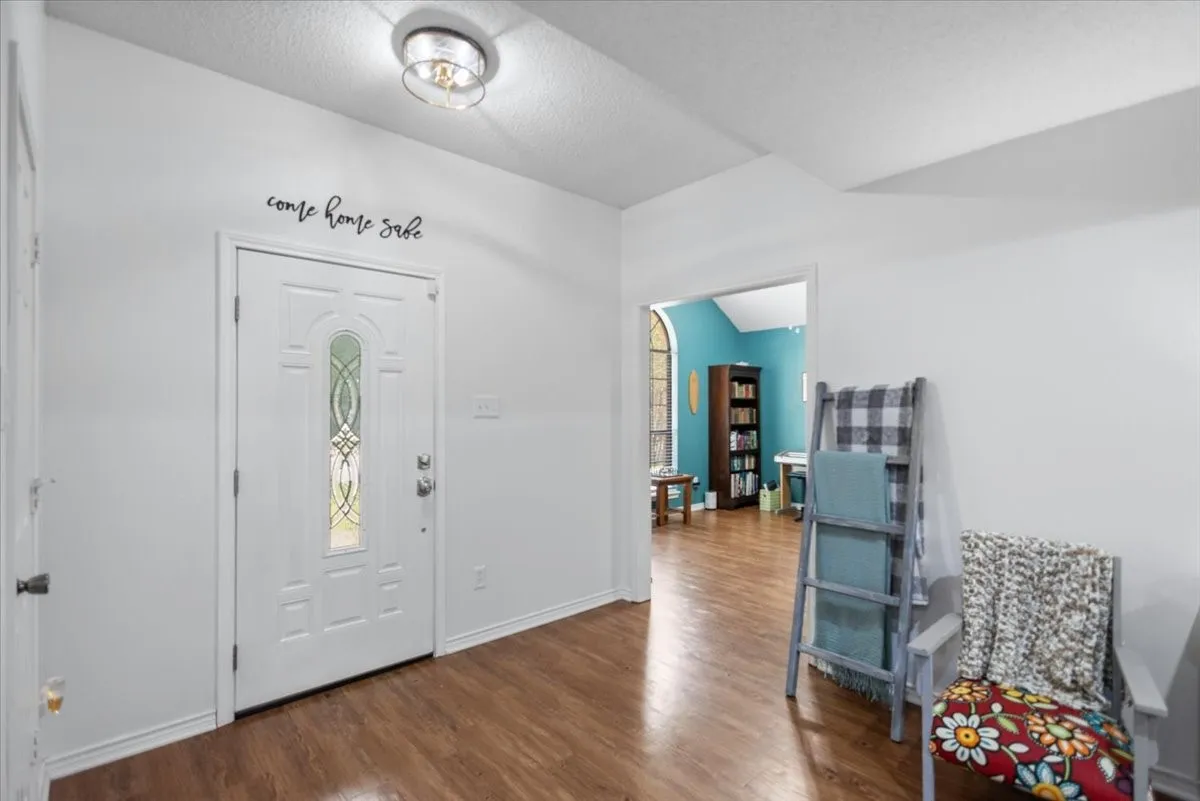 Entryway featuring wood-finish flooring, a white paneled door with decorative glass insert, and a semi-flush mount ceiling light fixture