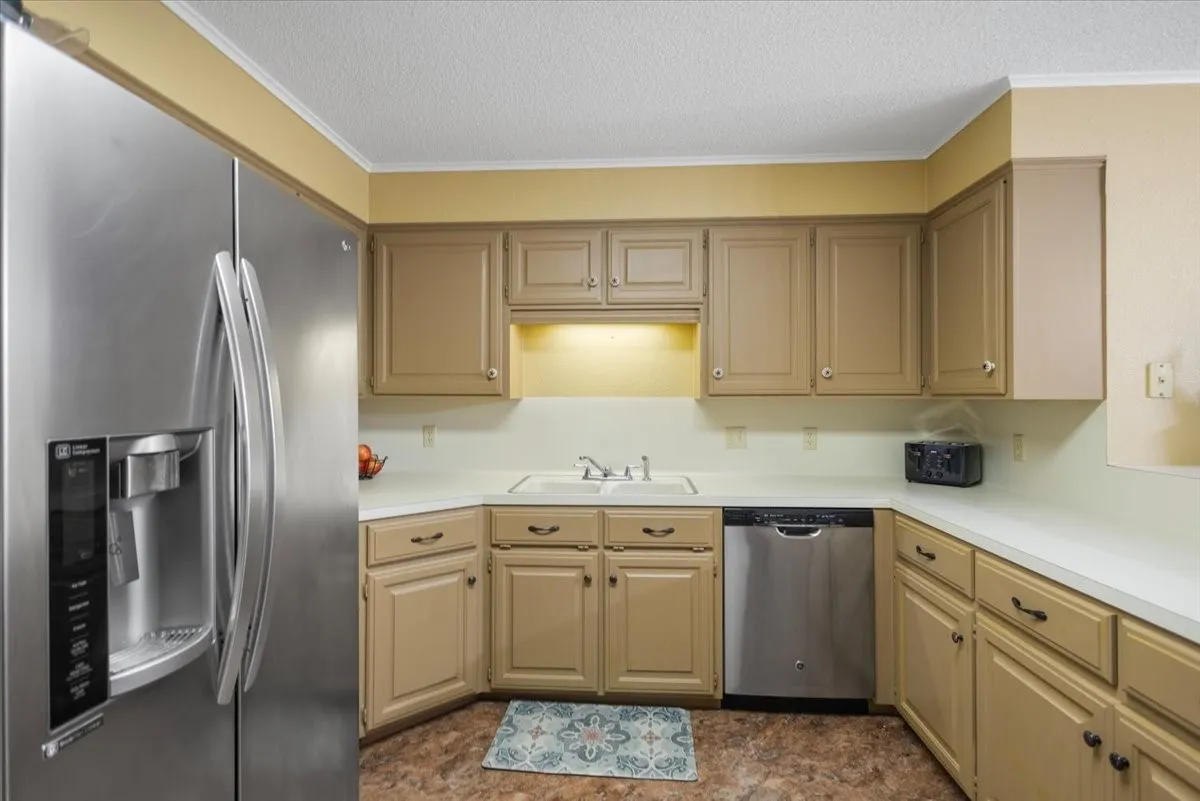 Kitchen featuring stainless steel appliances, solid surface countertops, and ample cabinetry