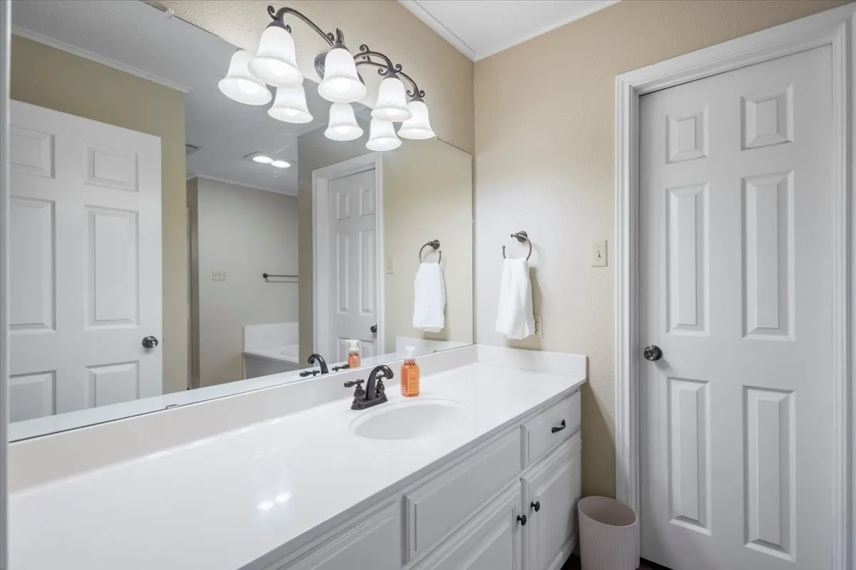 Bathroom vanity featuring a single sink, white countertop, and dark bronze faucet