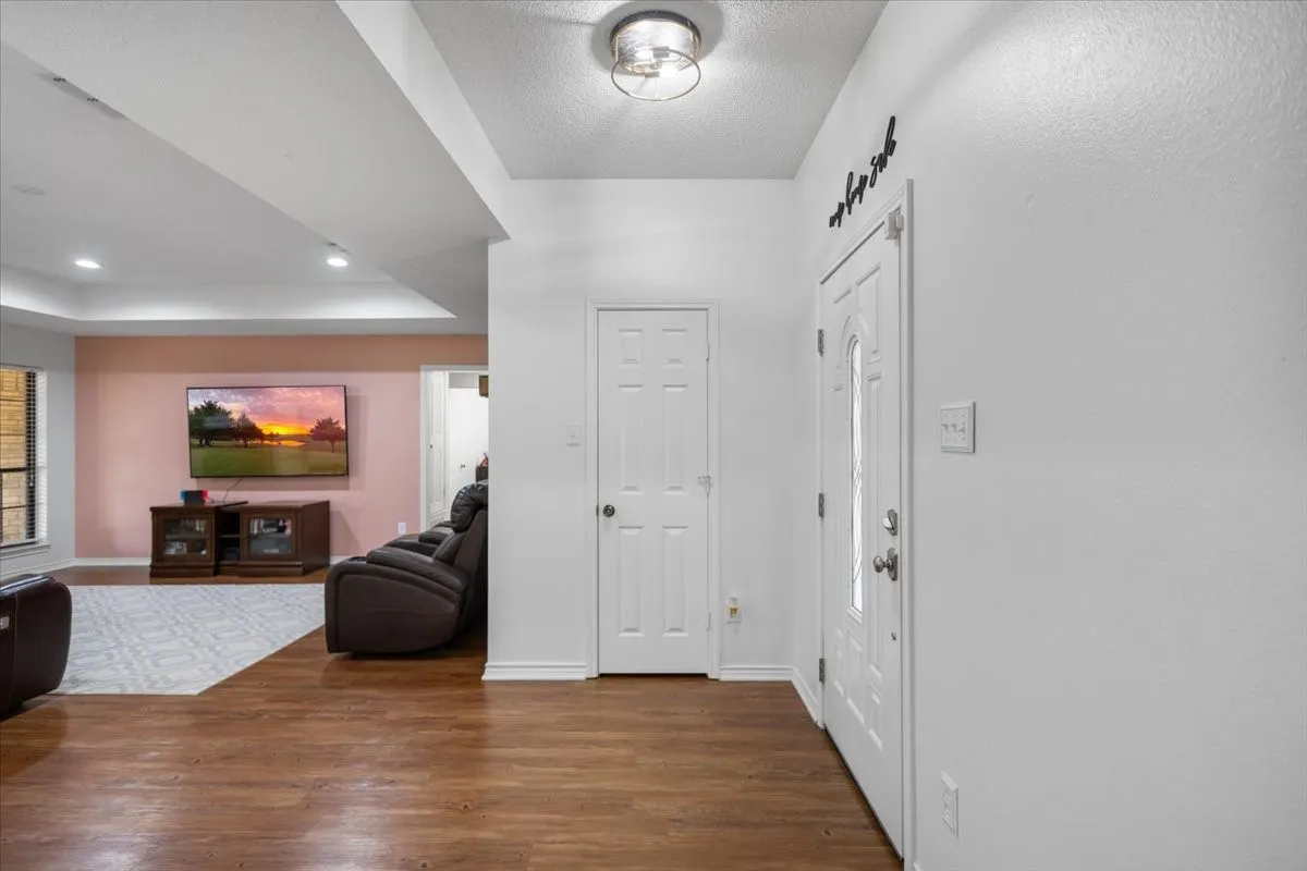 Entry area featuring wood-finish flooring, a white paneled entry door with frosted glass inserts, and an overhead semi-flush mount light fixture