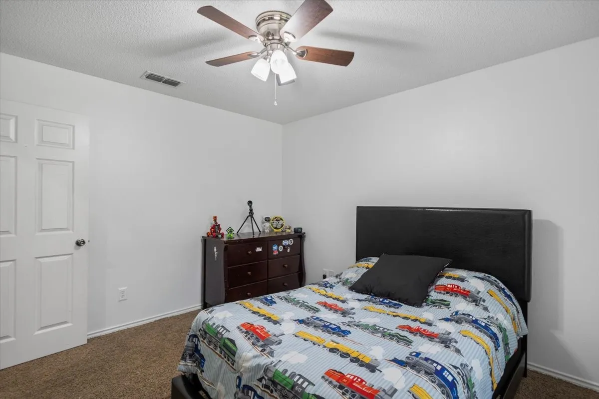 Carpeted room featuring a ceiling fan with integrated lighting, white walls, and a white paneled door