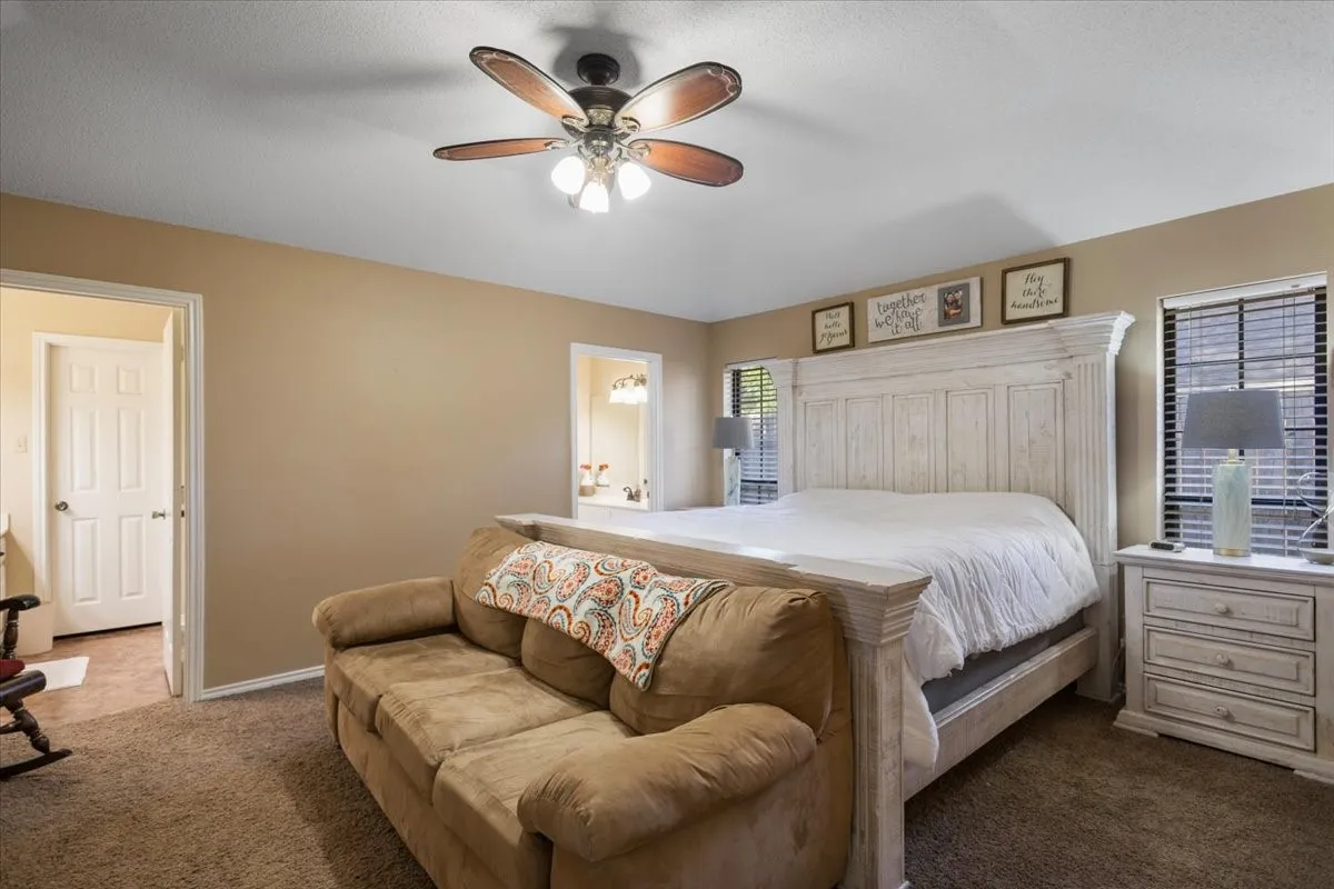 Spacious bedroom featuring carpet flooring, a ceiling fan with integrated lighting, and two windows with​​‌​​​​‌​​‌‌​‌‌​​​‌‌​‌​‌​‌​​​‌​​ blinds