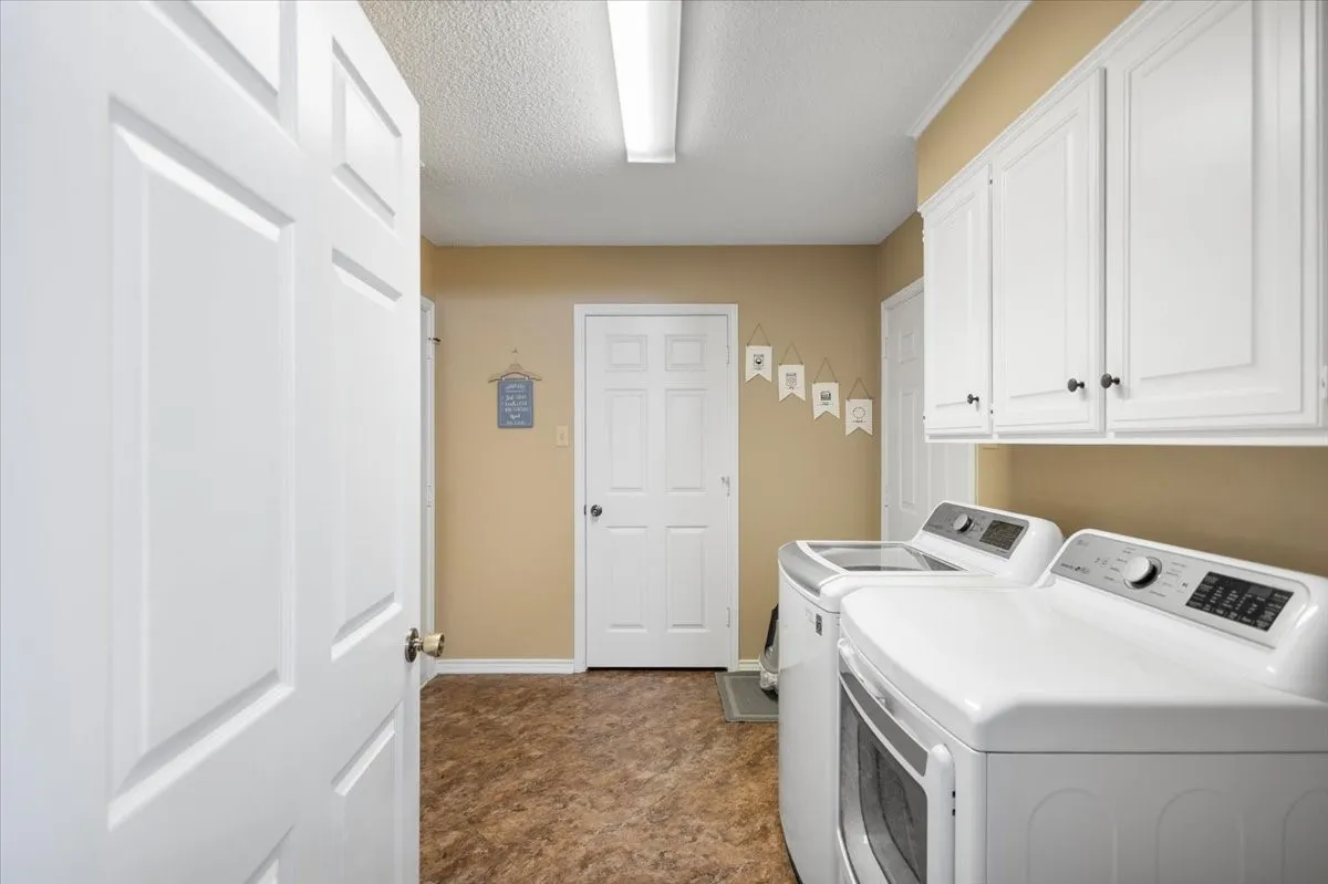 Dedicated laundry room featuring white cabinetry, brown-toned flooring, and neutral wall paint