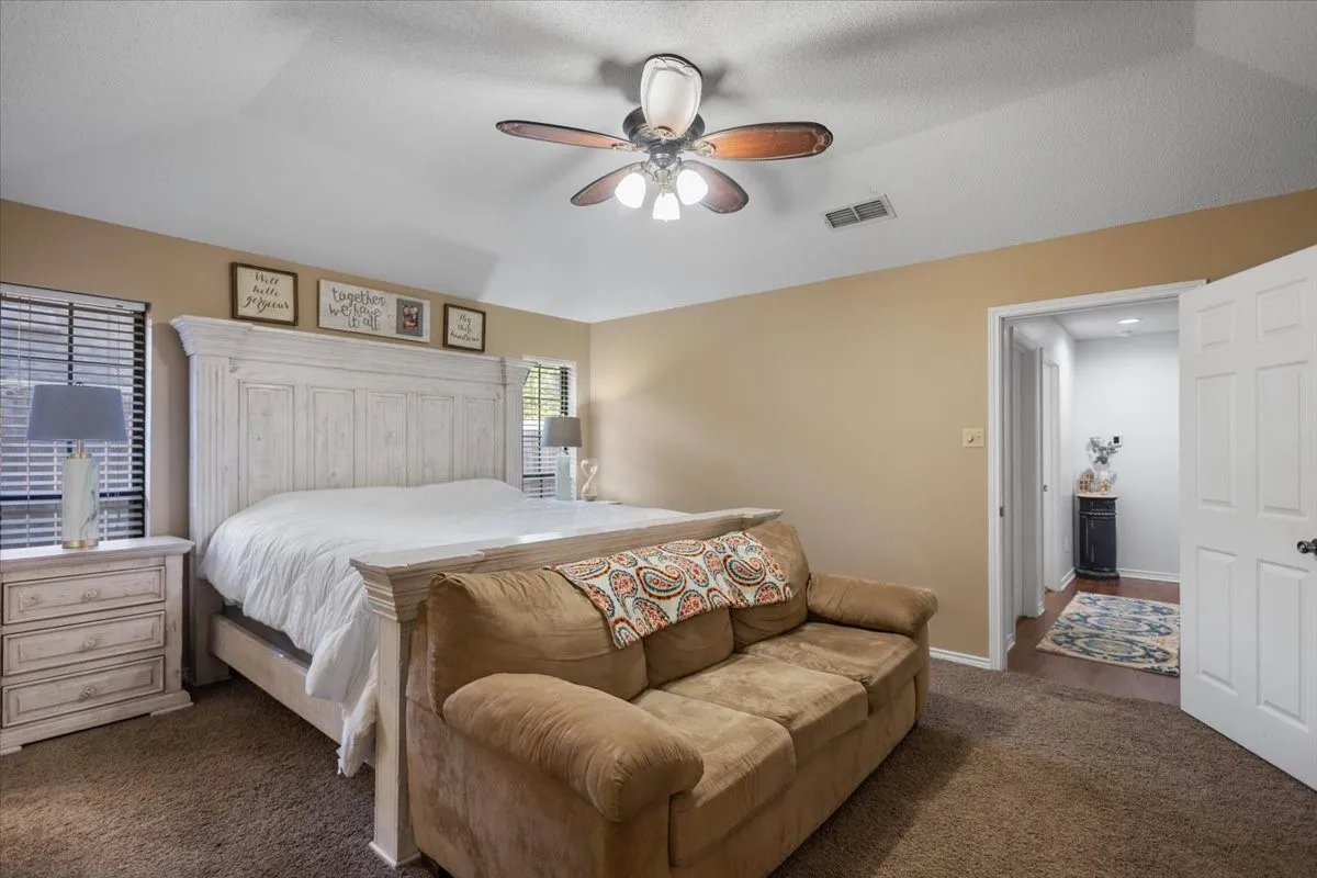 Carpeted bedroom featuring neutral-toned walls and a ceiling fan with integrated lighting