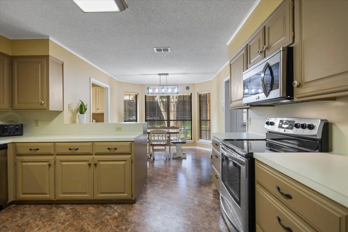 Kitchen featuring wood-finish cabinetry, white countertops, stainless steel appliances, and wood-finish flooring