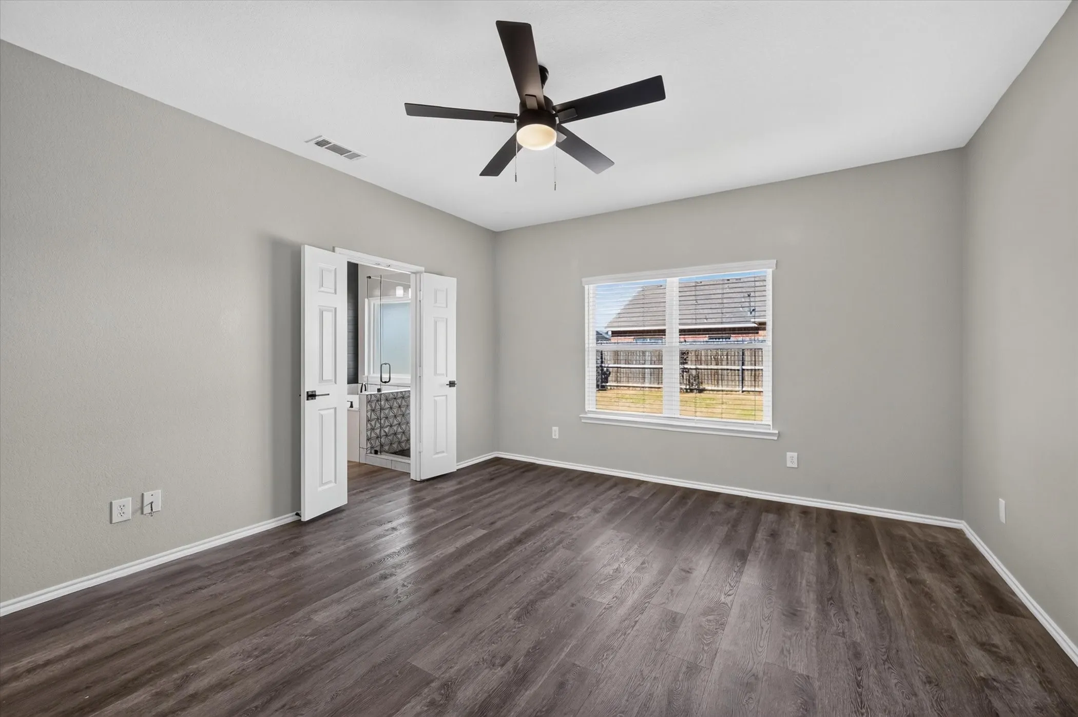Wood-finish flooring with light gray wall paint, a white-framed window, and a ceiling fan