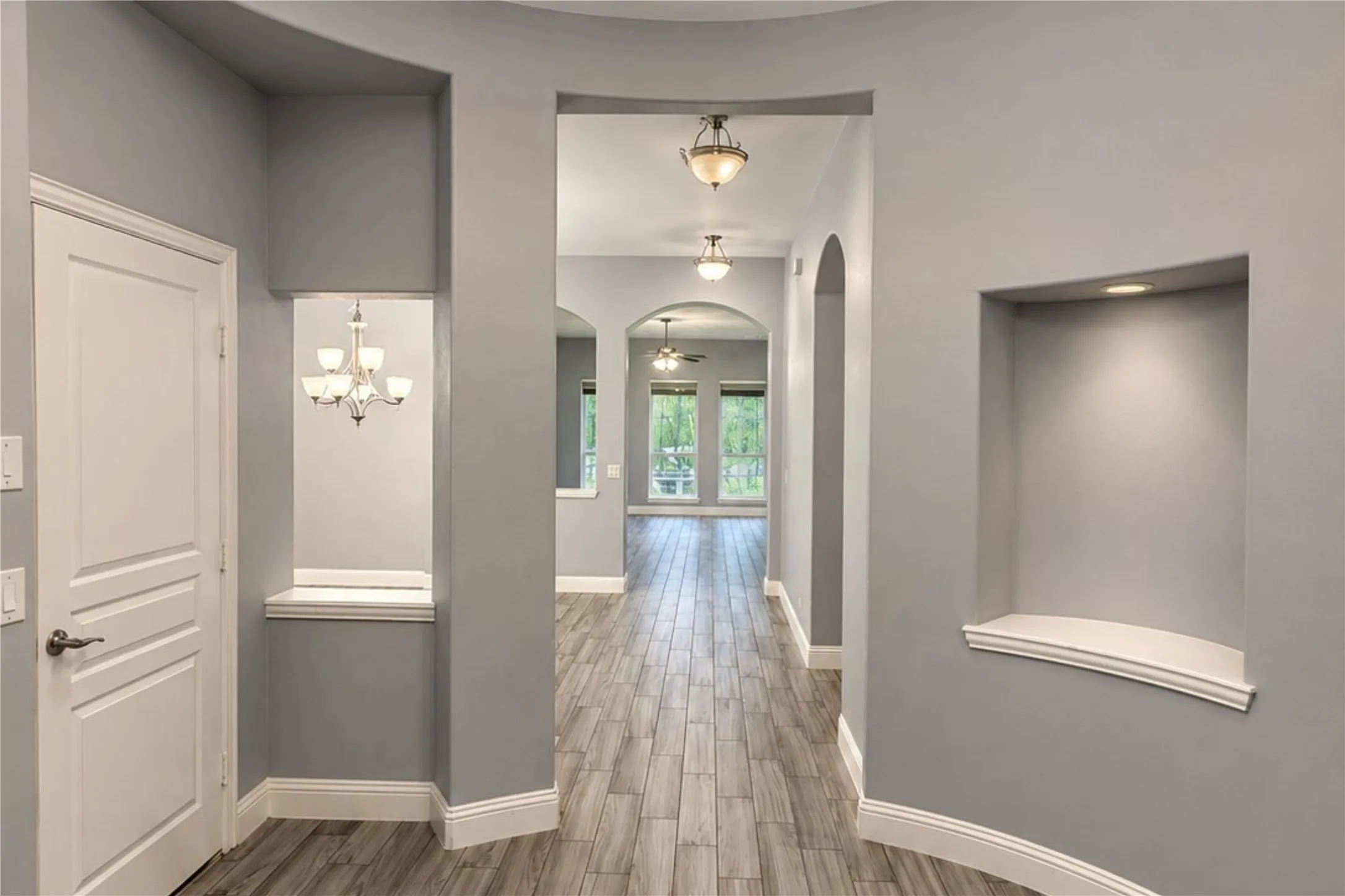 Hallway with wood-finish flooring, recessed lighting, arched doorways, and decorative wall niches