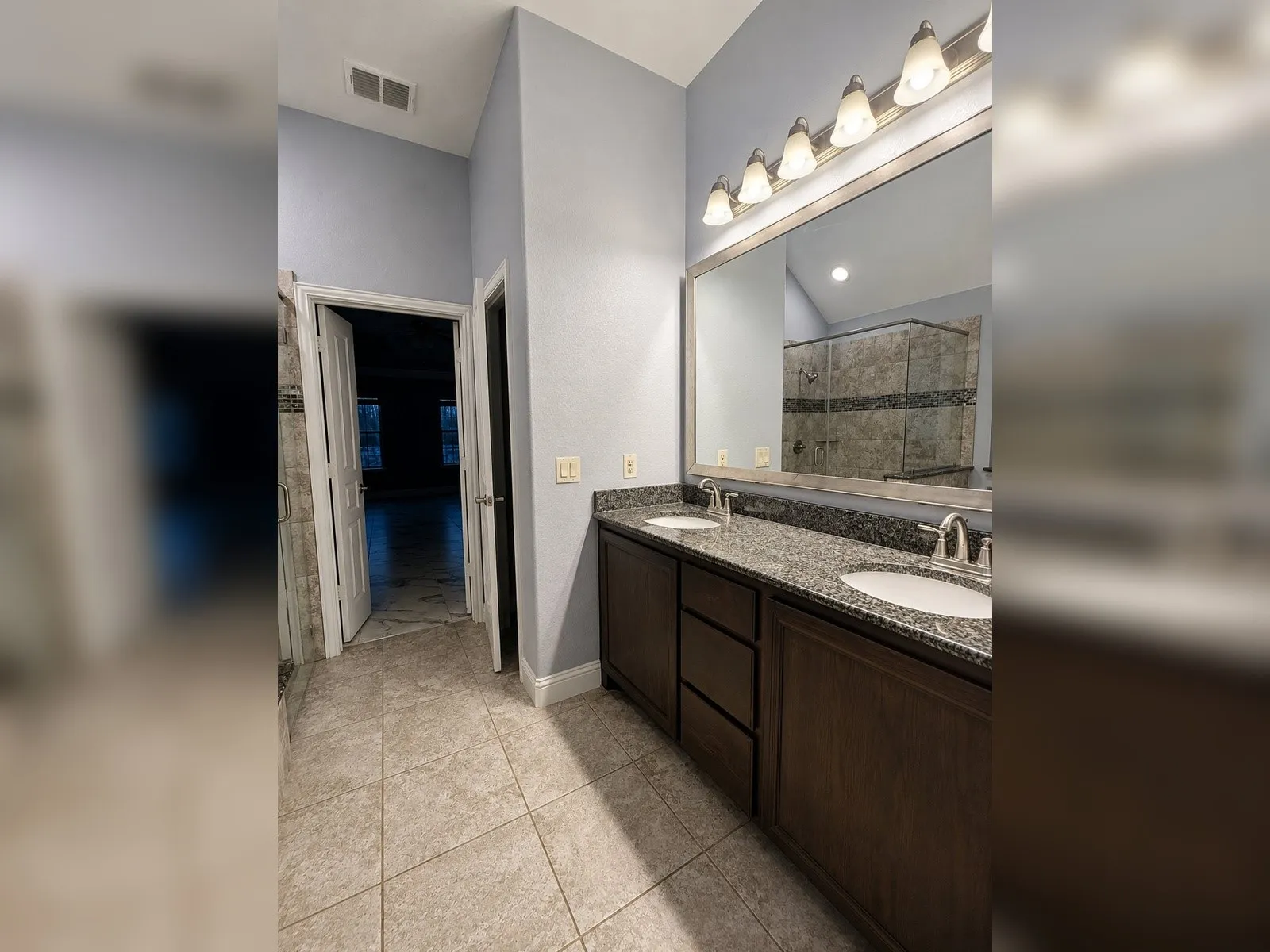 Dual vanity with granite countertop, integrated sinks, and ample storage cabinetry