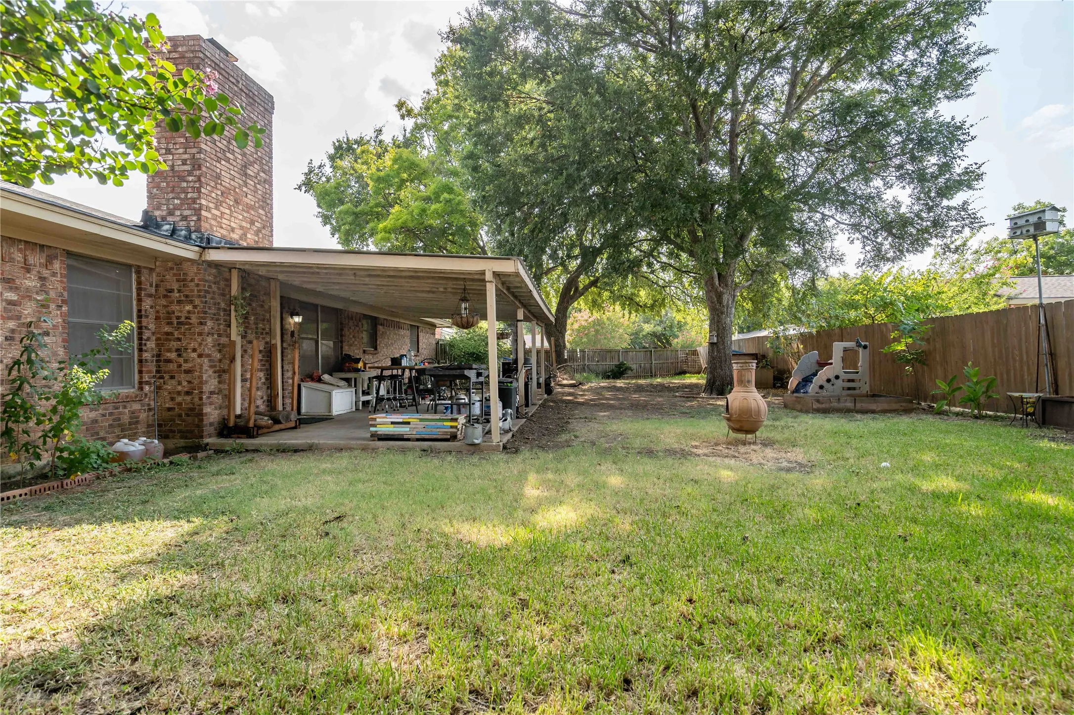 Covered patio helps turn this huge wooden fenced backyard into a playground or entertaining area.