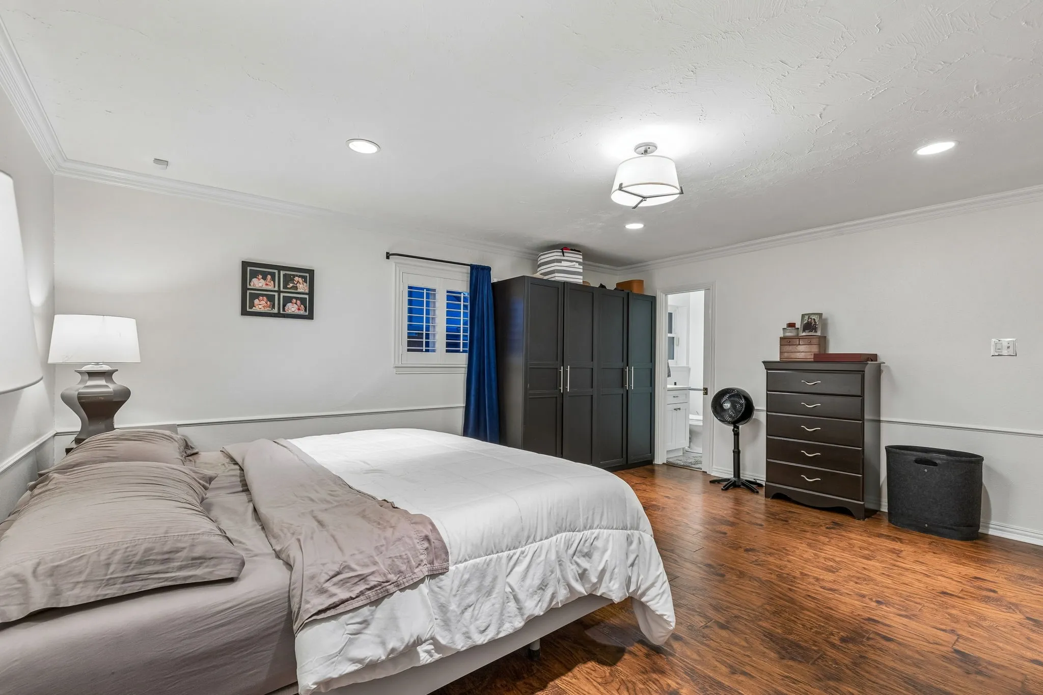 Bedroom with crown molding, dark wood-style flooring, recessed lighting, and connected bathroom