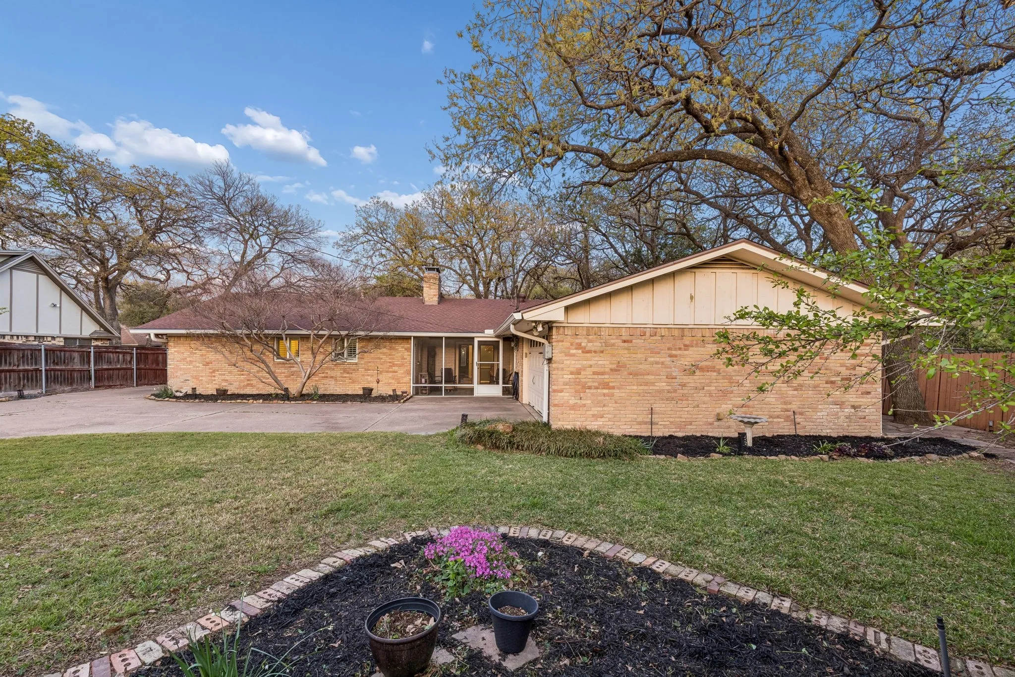 Back of property featuring brick siding, a chimney, board and batten siding, a sunroom, and a patio area