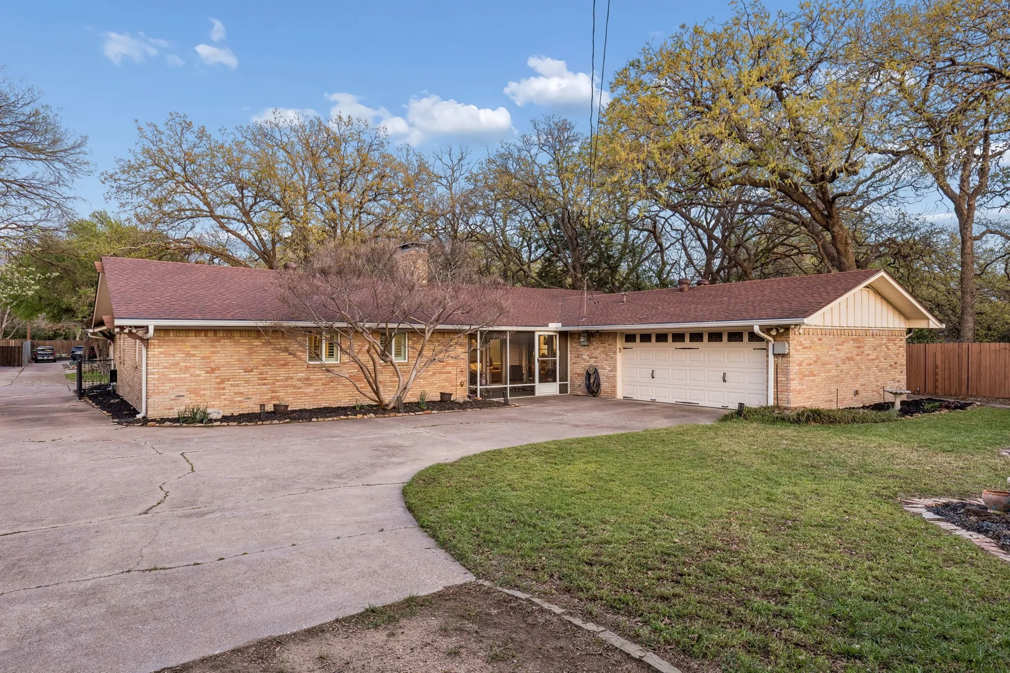 View of front of home with concrete driveway, a garage, brick siding, and a shingled roof
