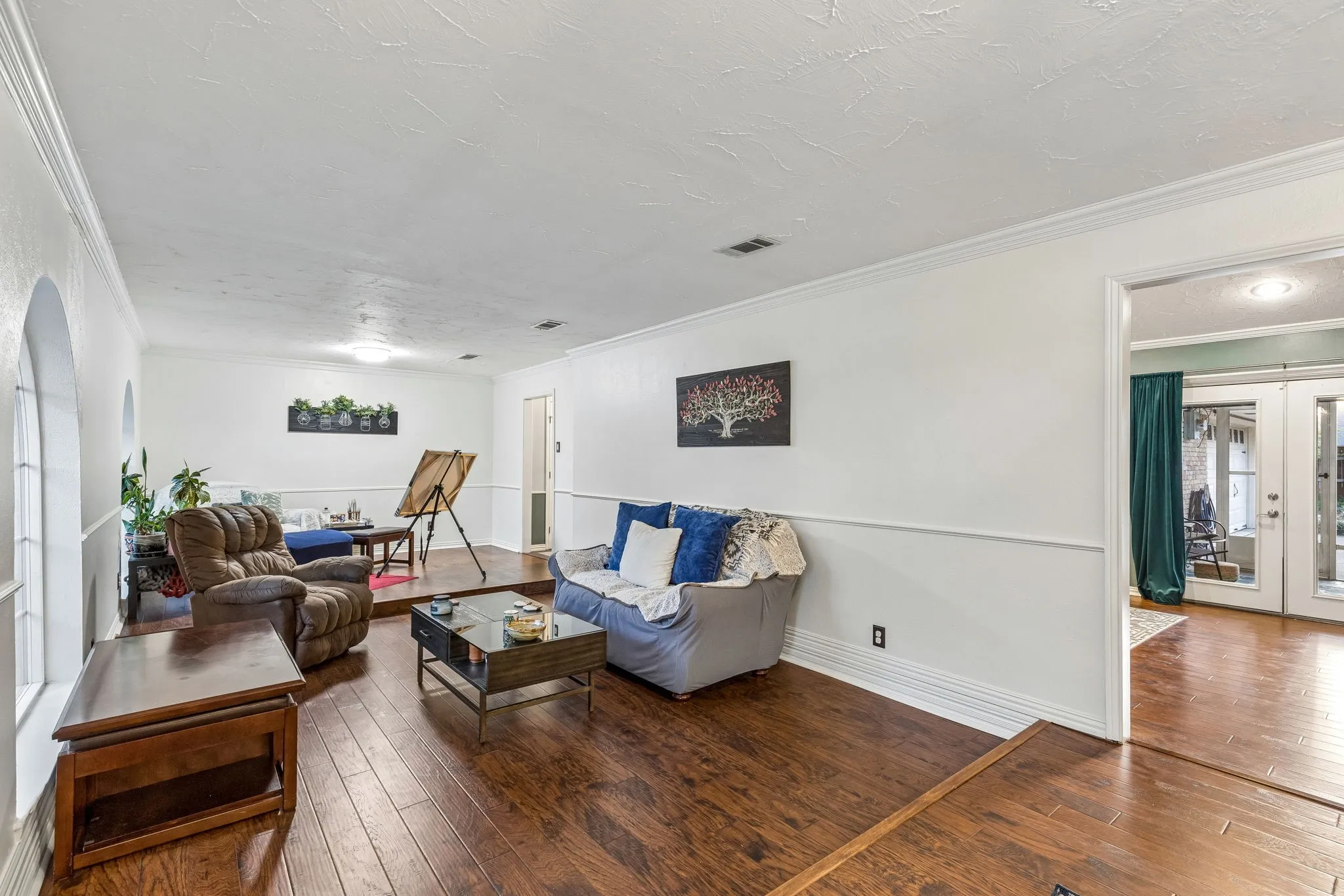 Living room with french doors, ornamental molding, hardwood / wood-style flooring, and a textured ceiling