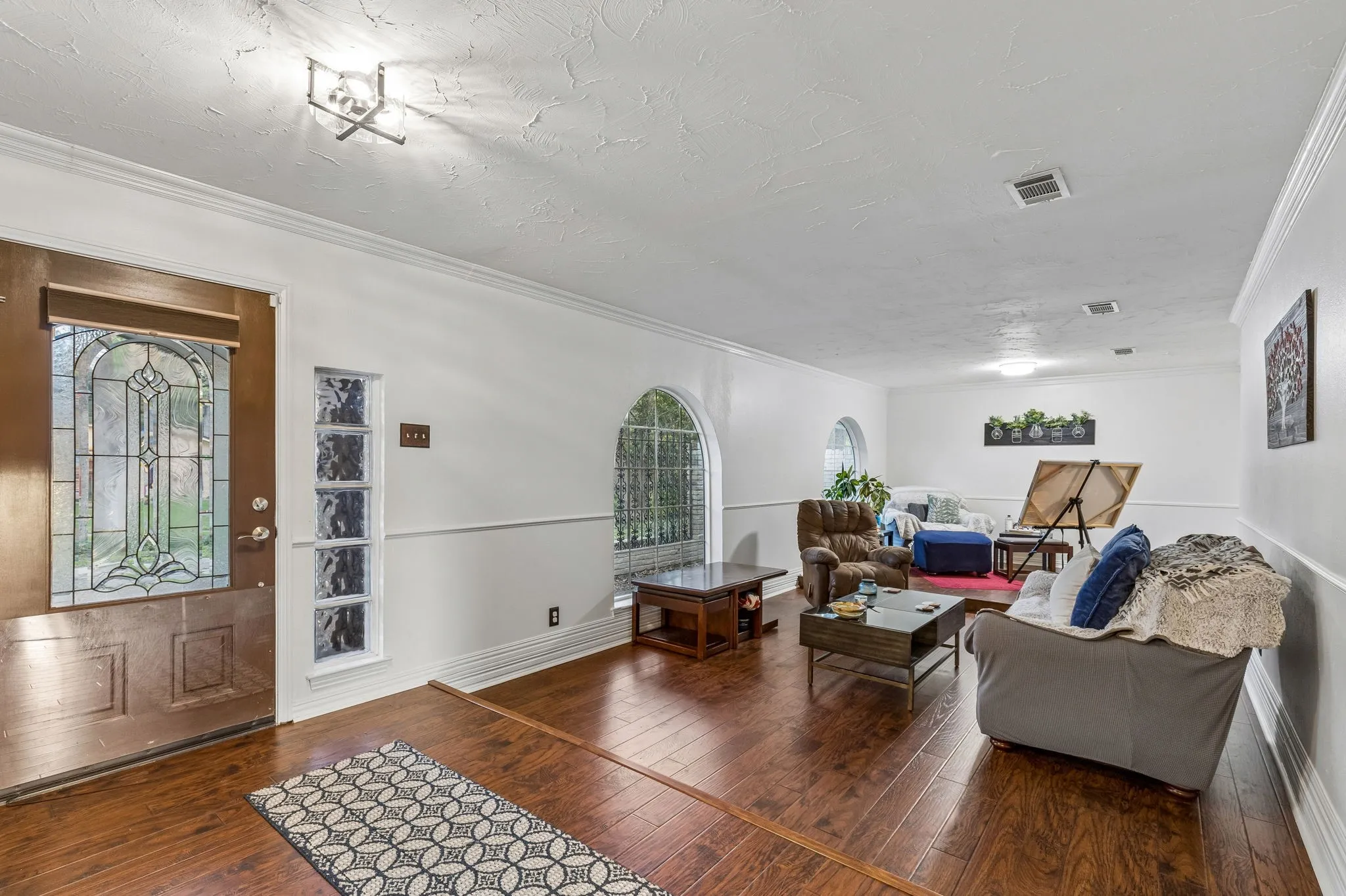 Living room featuring crown molding, dark wood-style flooring, plenty of natural light, and a textured ceiling