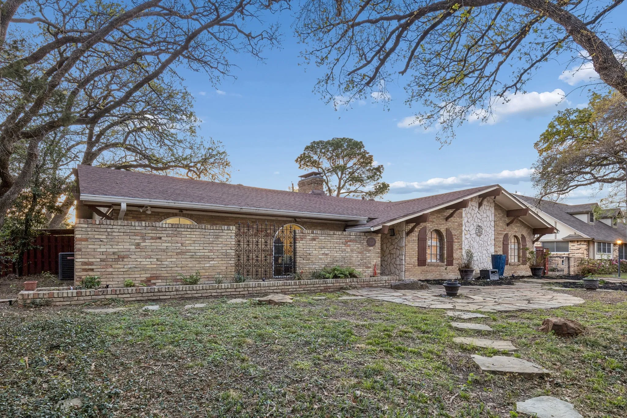 View of front of house with brick siding, a chimney, a patio, and roof with shingles