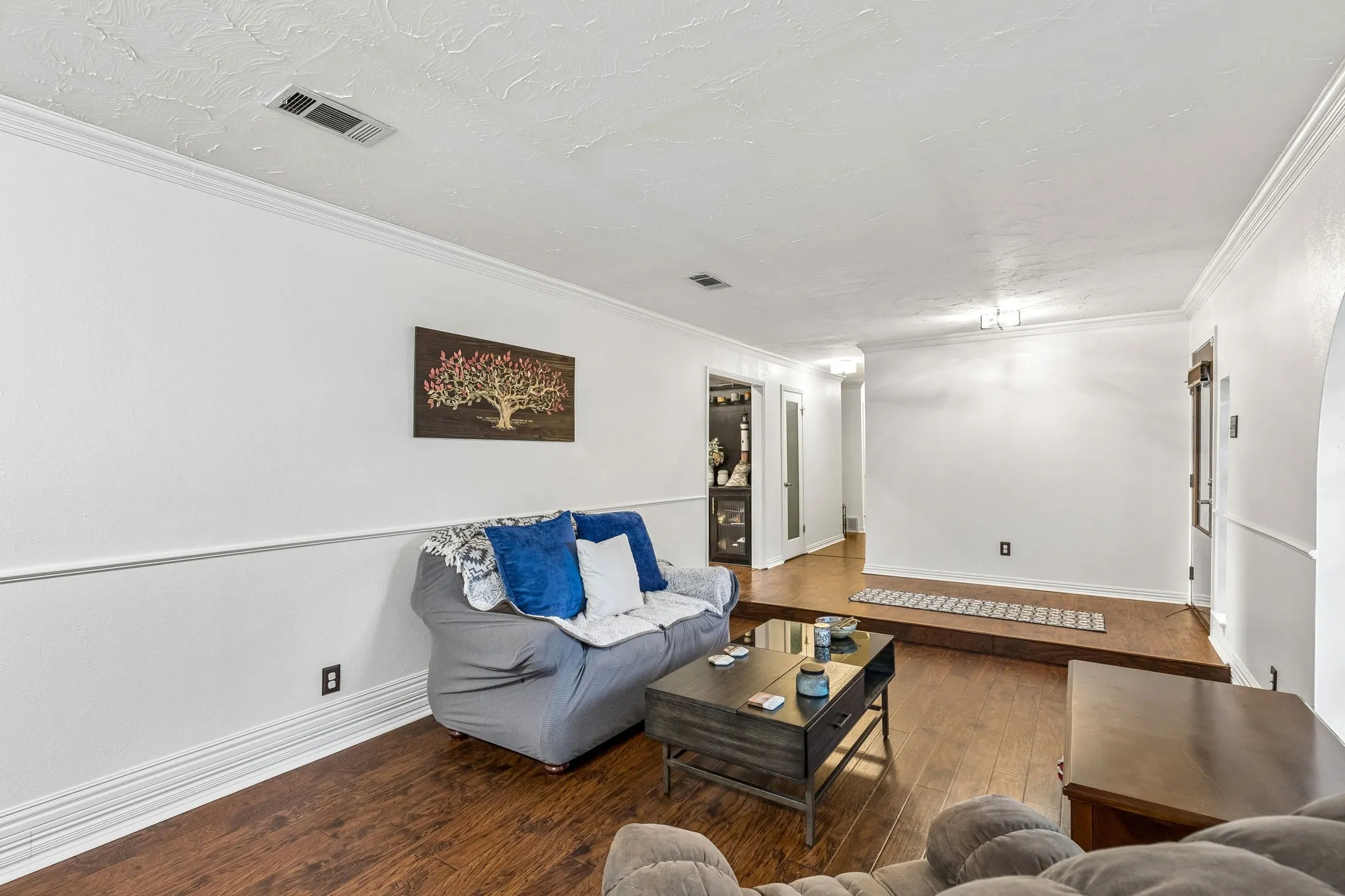 Living area featuring dark wood-style floors and crown molding