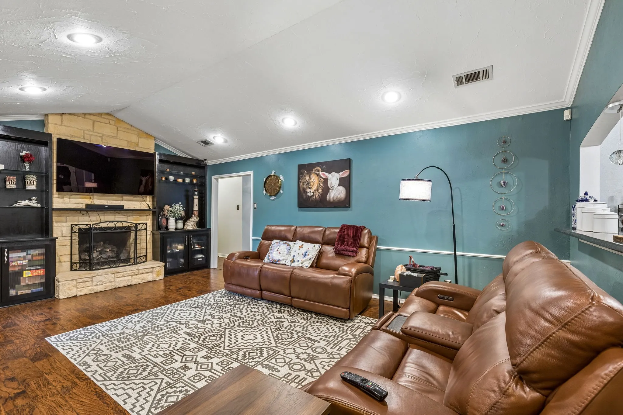 Living area featuring wood finished floors, ornamental molding, and a stone fireplace