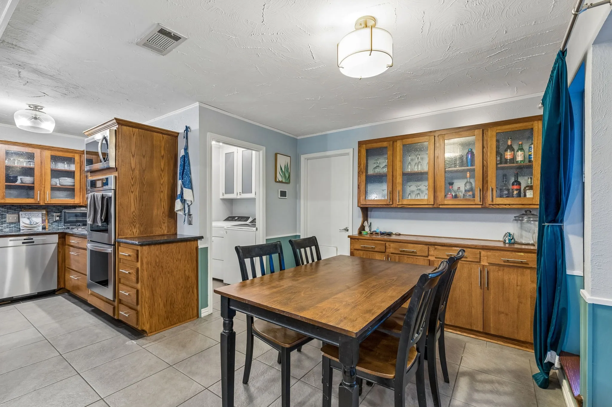 Dining room with separate washer and dryer, ornamental molding, light tile patterned floors, and a textured ceiling