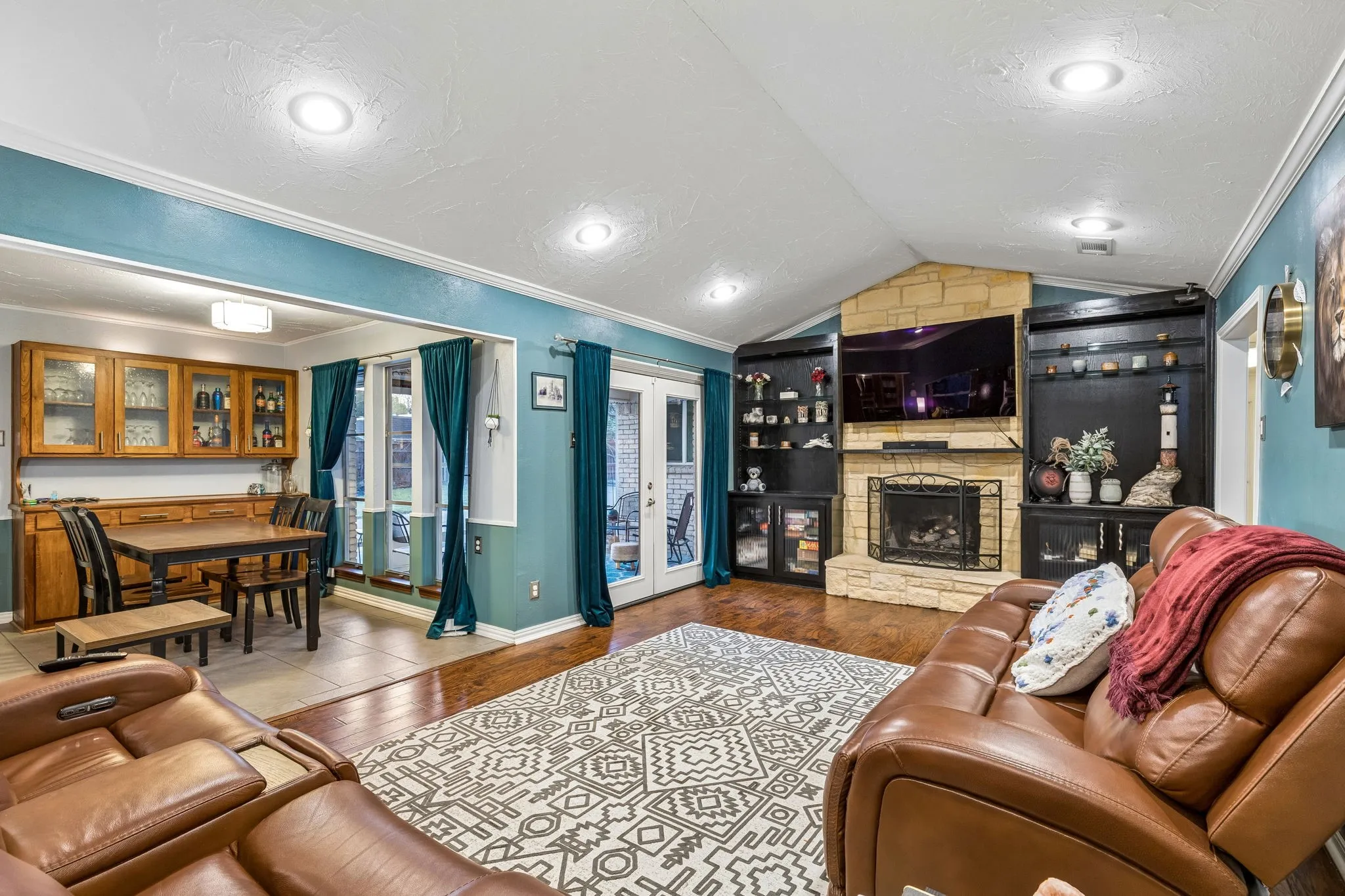 Living area with crown molding, a stone fireplace, and dark wood-style floors