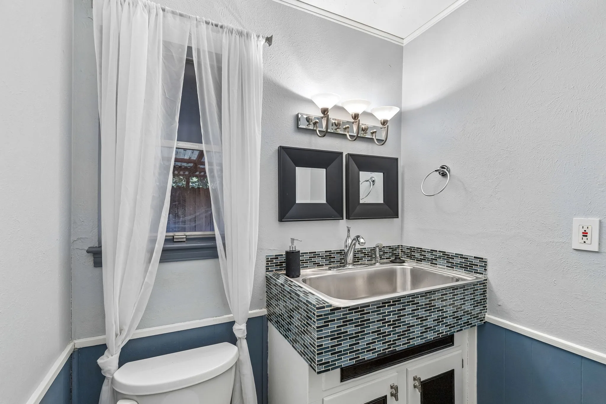 Bathroom with a textured wall, vanity, wainscoting, and crown molding