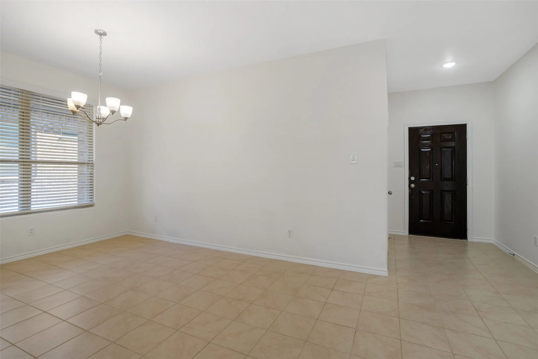 Spare room featuring a chandelier and light tile floors