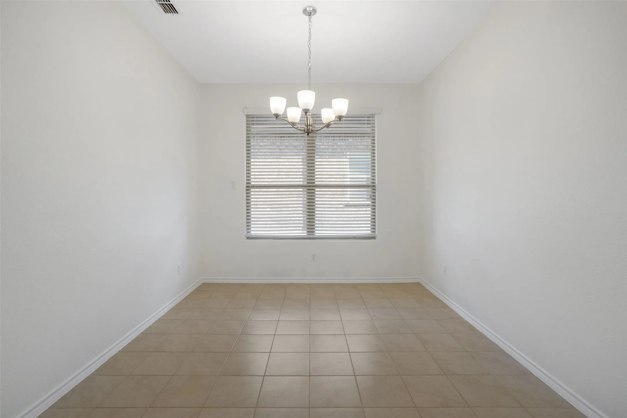 Unfurnished room with a notable chandelier and light tile flooring