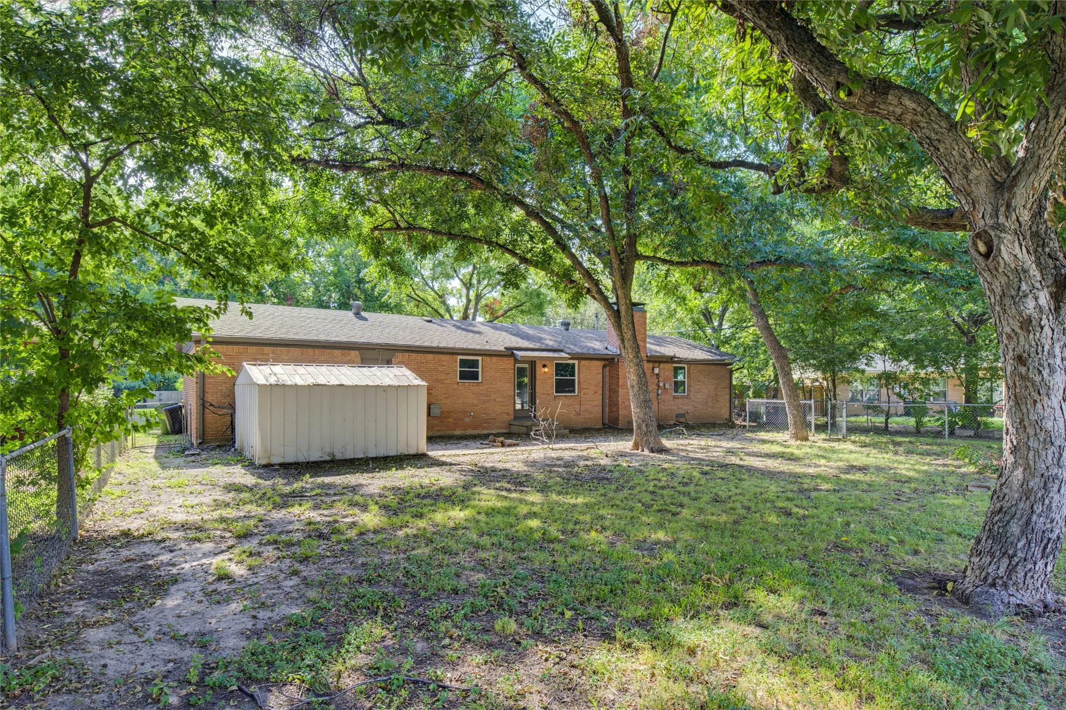 Large backyard with storage shed and mature trees