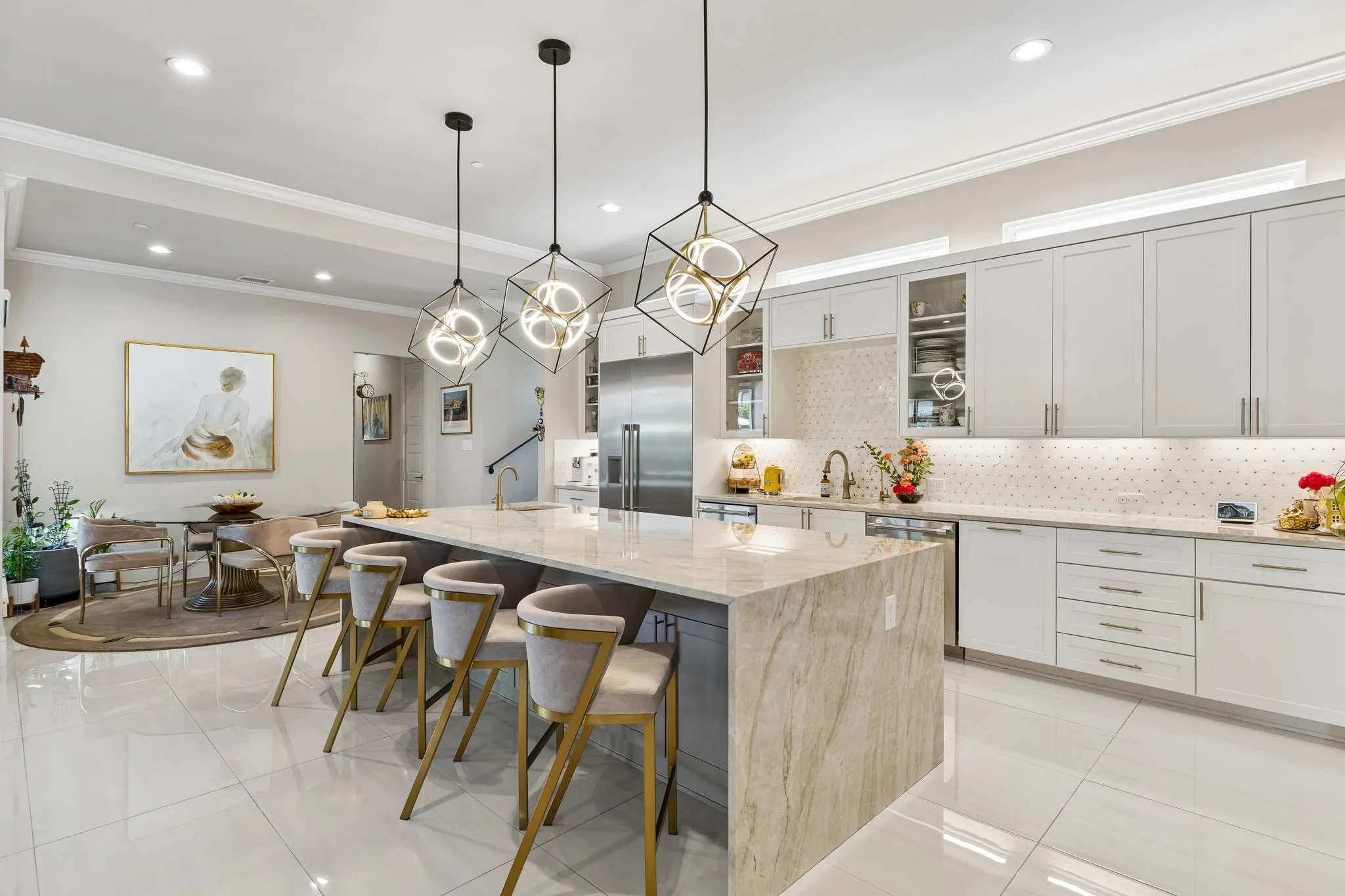 The kitchen features gorgeous Taj Mahal quartzite waterfall island & countertops and built-in Thermador appliances including refrigerator, commercial range, double ovens, two dishwashers, microwave, and vented hood!