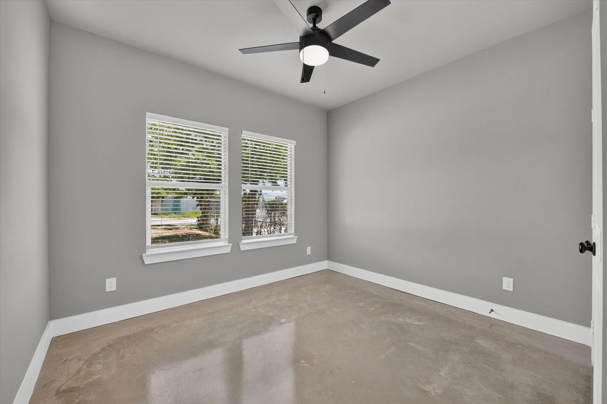 Front bedroom with window shades and ceiling fan.