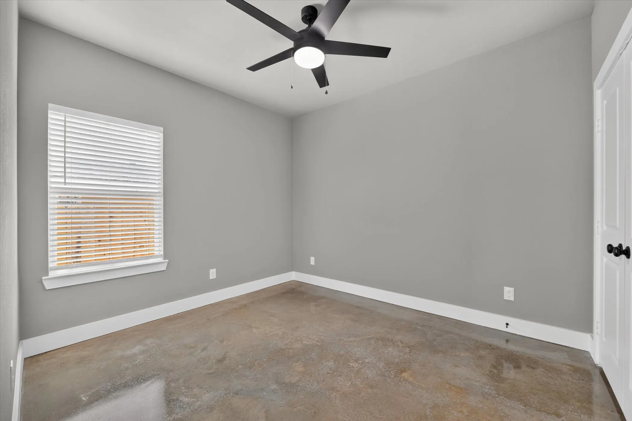 Middle bedroom with window shades and ceiling fan.