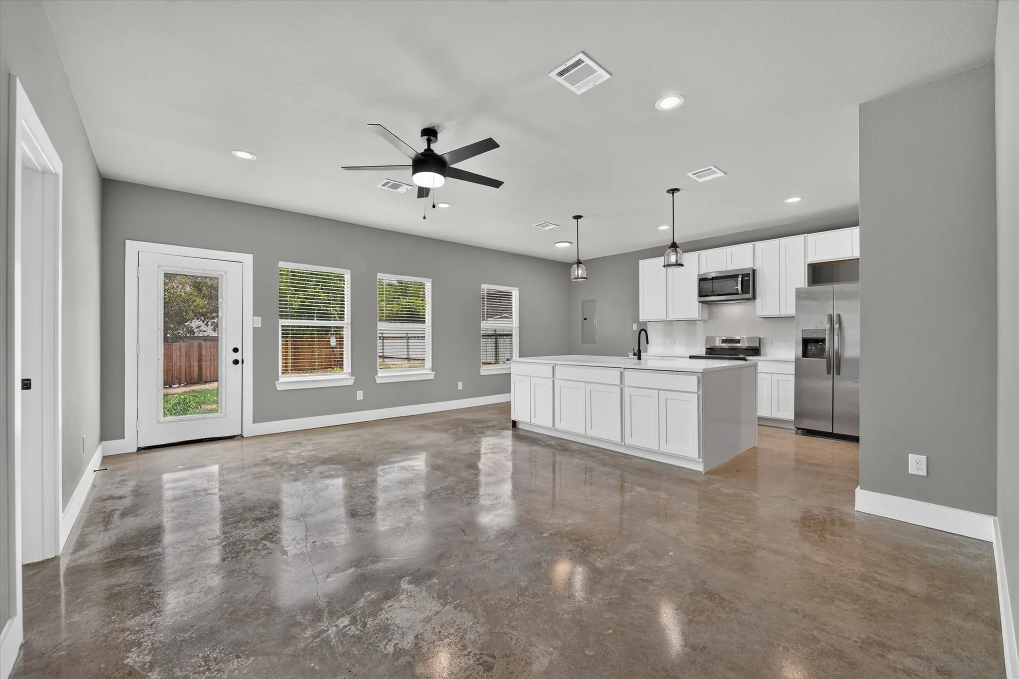 Large open living room with kitchen and entry to backyard.  Polished concrete flooring throughout home.