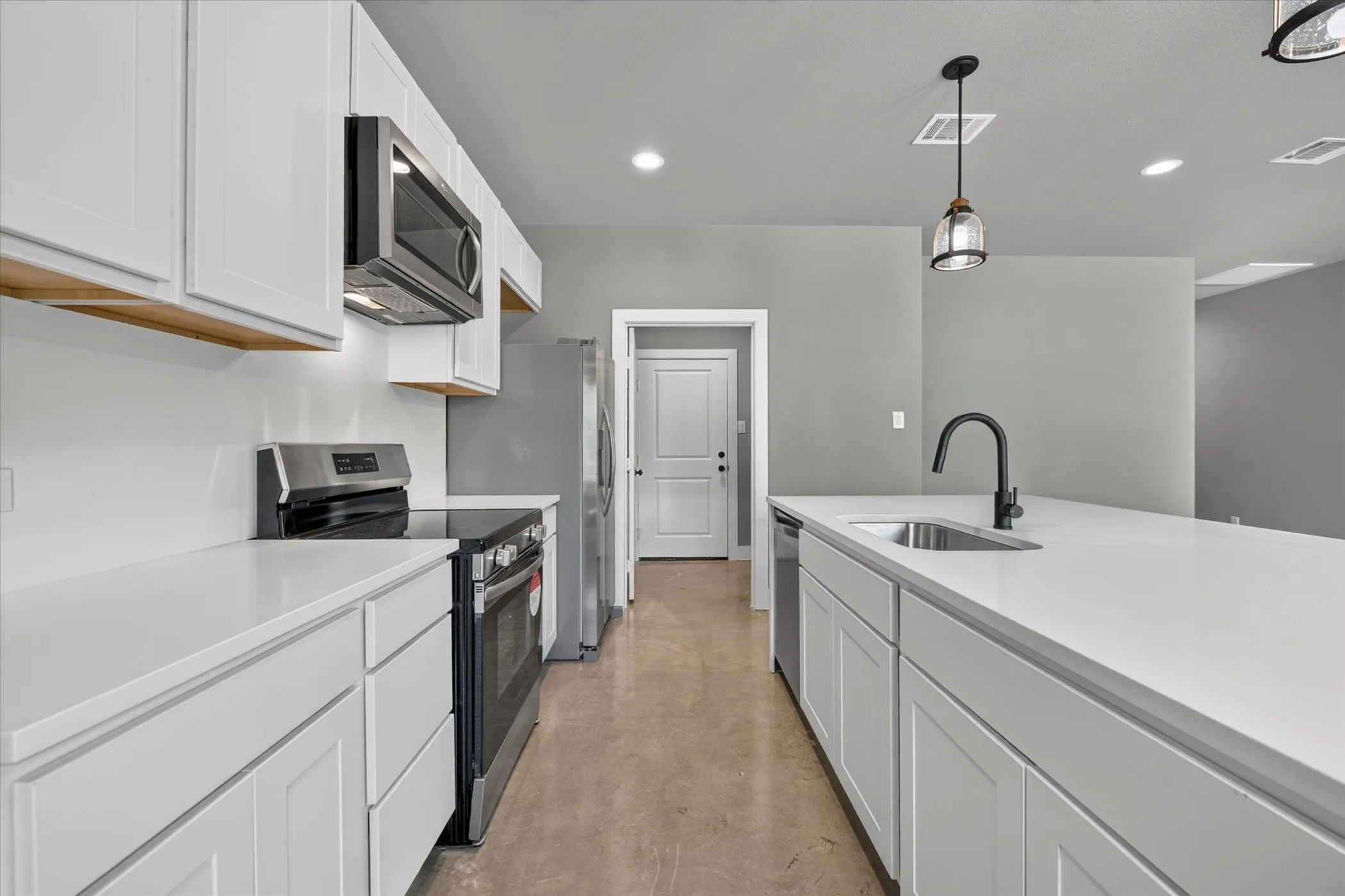 Kitchen includes full appliance package and leads to utility room and garage door beyond.