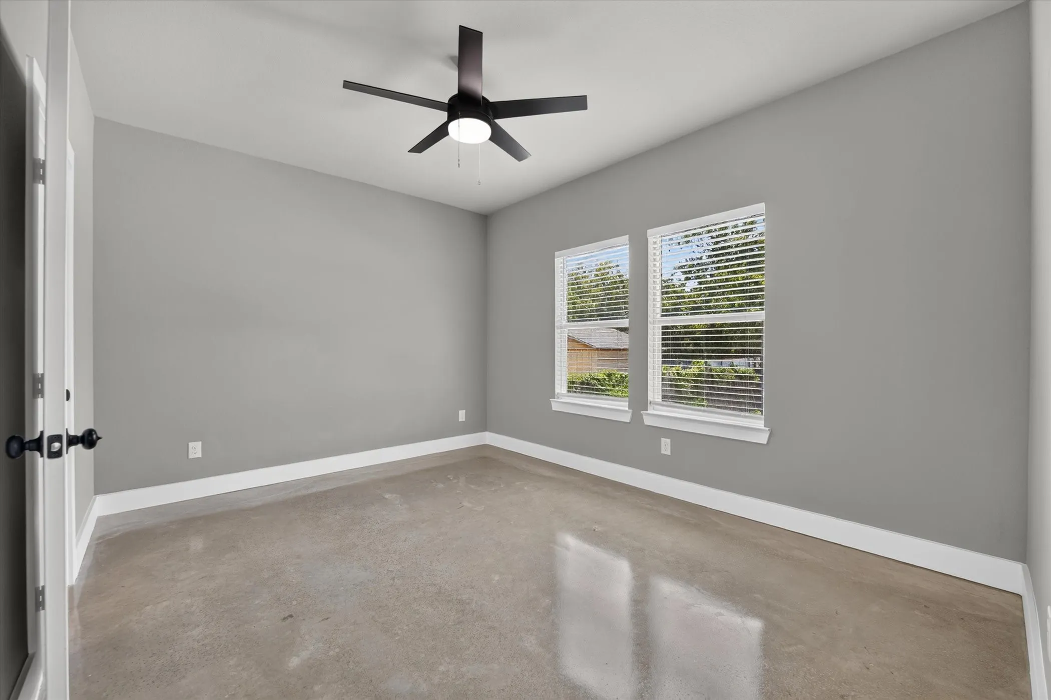 Primary bedroom features shaded windows, ceiling fan, and view of backyard.