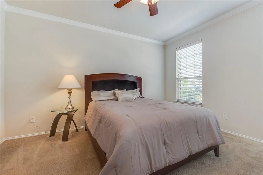 STAGED - Owner's Suite featuring ceiling fan, ensuite bath with walk-in closet, neutral wall tones, and crown molding