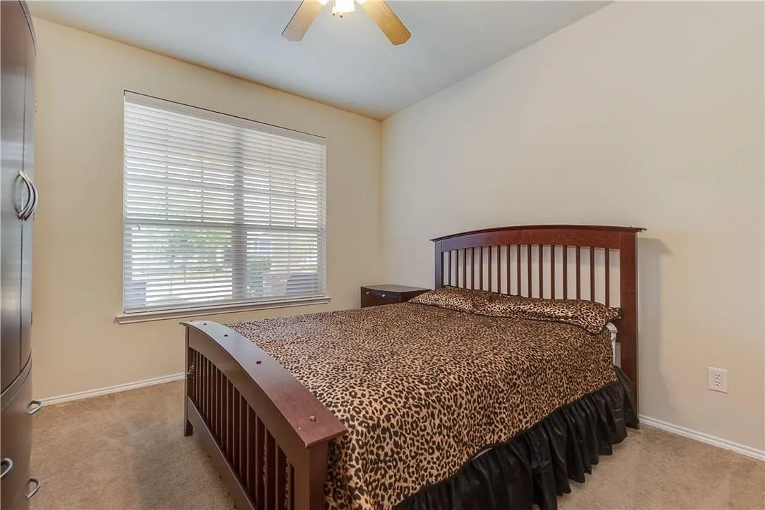 STAGED - Carpeted room featuring a large window with horizontal blinds, ceiling fan, and neutral wall paint.