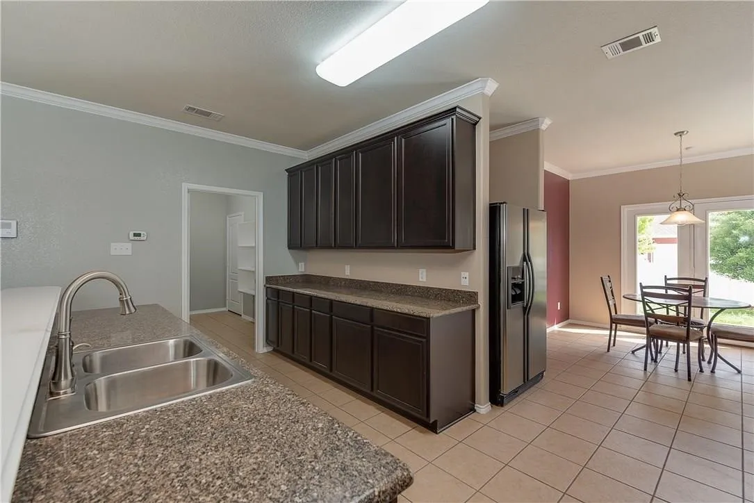STAGED - Kitchen featuring granite counters, undermount double sink, black appliances: dishwasher, glass-top range, microwave & refrigerator.