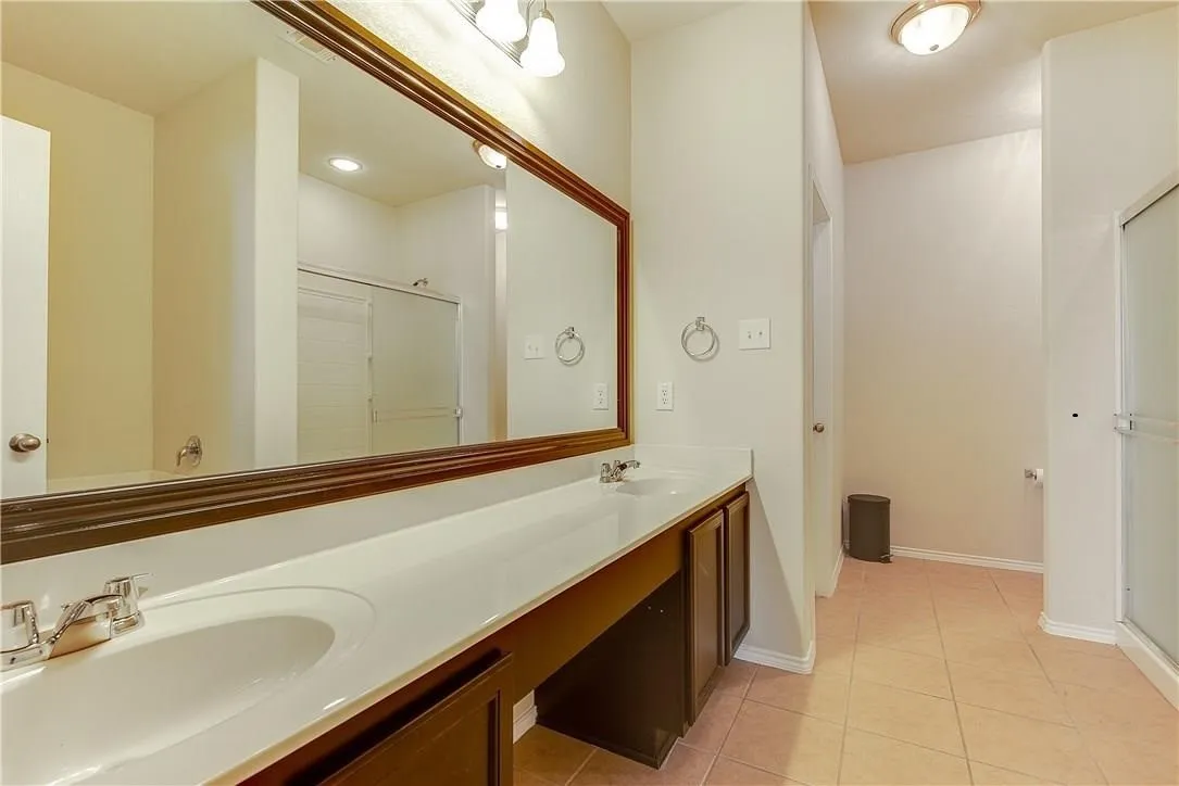 Owner's Ensuite bath features dual sink vanity with makeup desk, garden tub, separate double shower with walk-in closet, neutral wall tones, and crown molding.