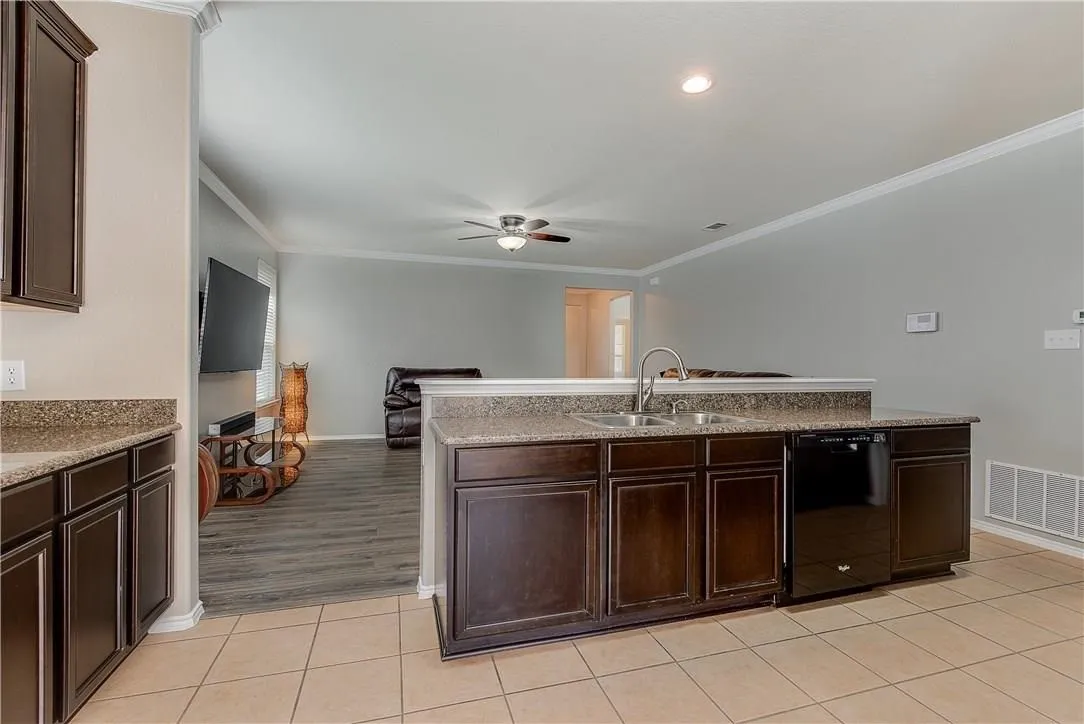 STAGED - Kitchen featuring granite counters, undermount double sink, black appliances: dishwasher, glass-top range, microwave & refrigerator.
