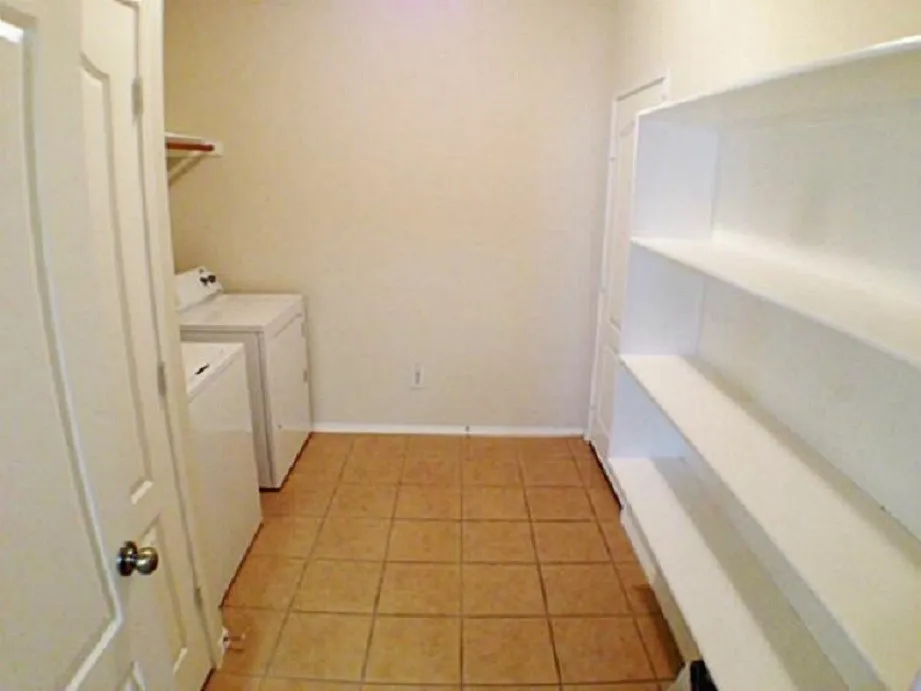 Kitchen Pantry and Utility combo room features Full-Sized Washer and Dryer, drip dry hanging area, neutral tile flooring, built-in shelving, light-toned walls, and access to the water heater and furnace closet.