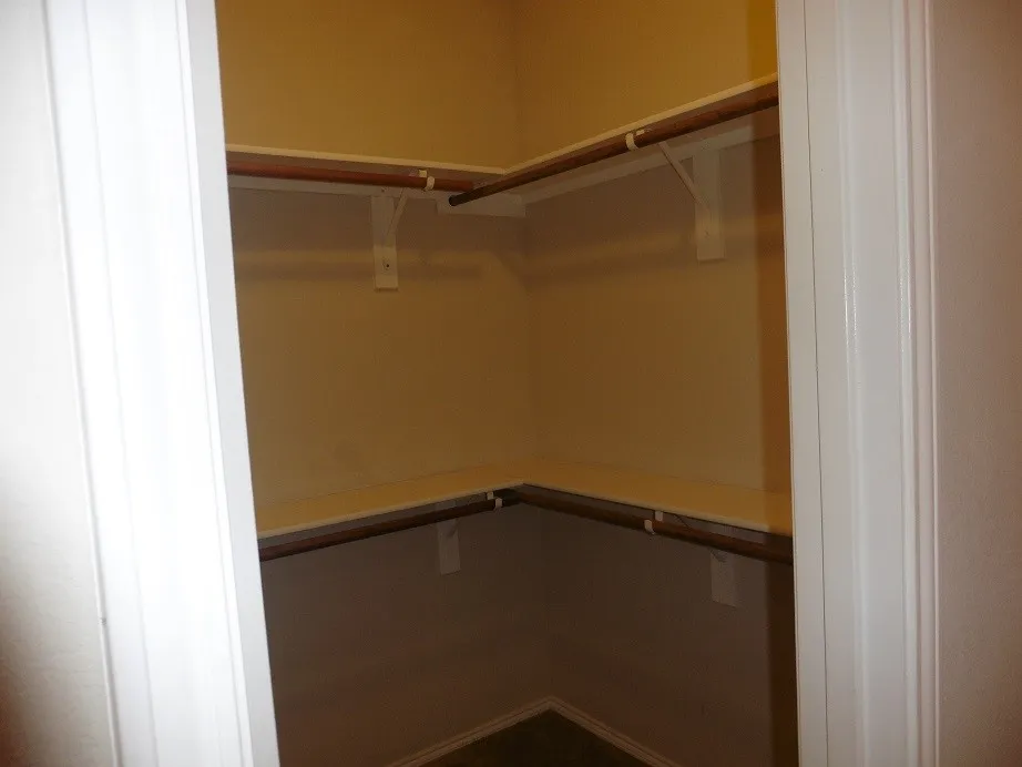 Walk-in closet featuring light-colored walls, white trim, and a multi-tiered shelving and hanging rod system