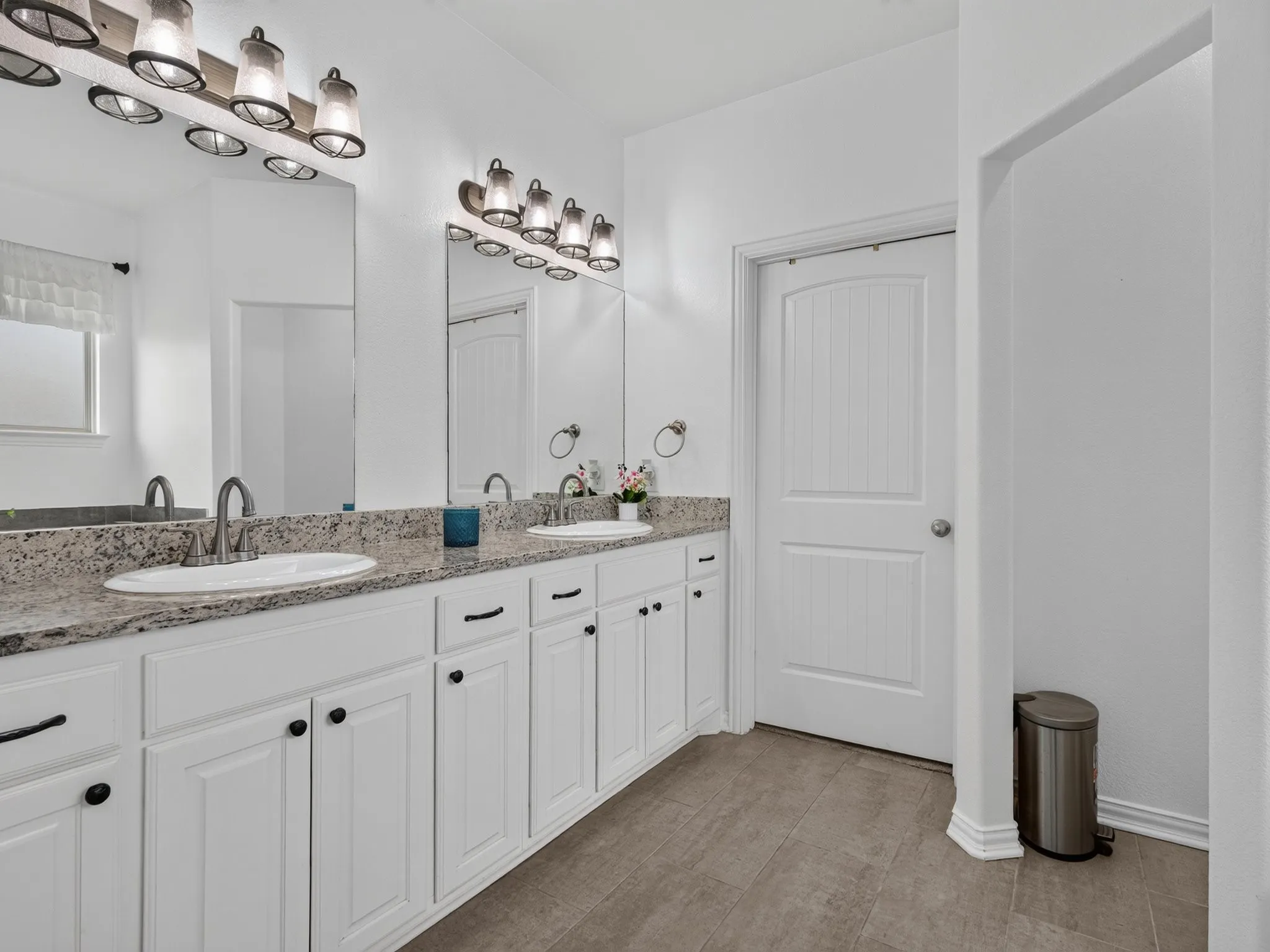 Primary bathroom with dual sinks, granite countertops, and built-in cabinetry.