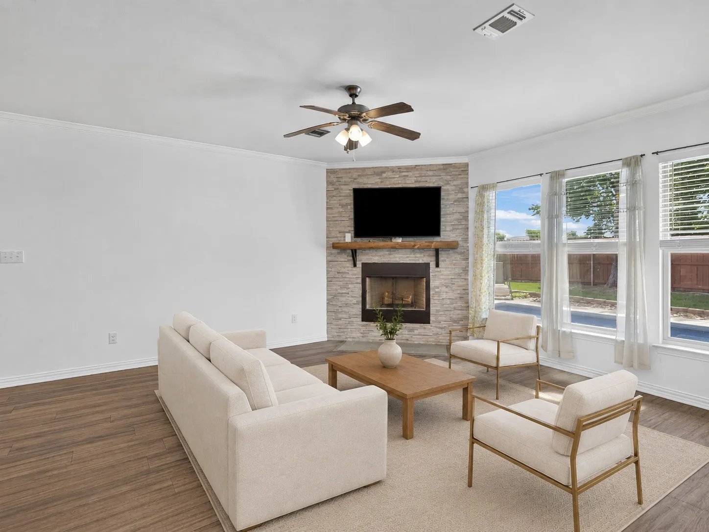 Living room with a floor-to-ceiling stacked stone wood-burning fireplace and abundant natural light. Virtually staged.
