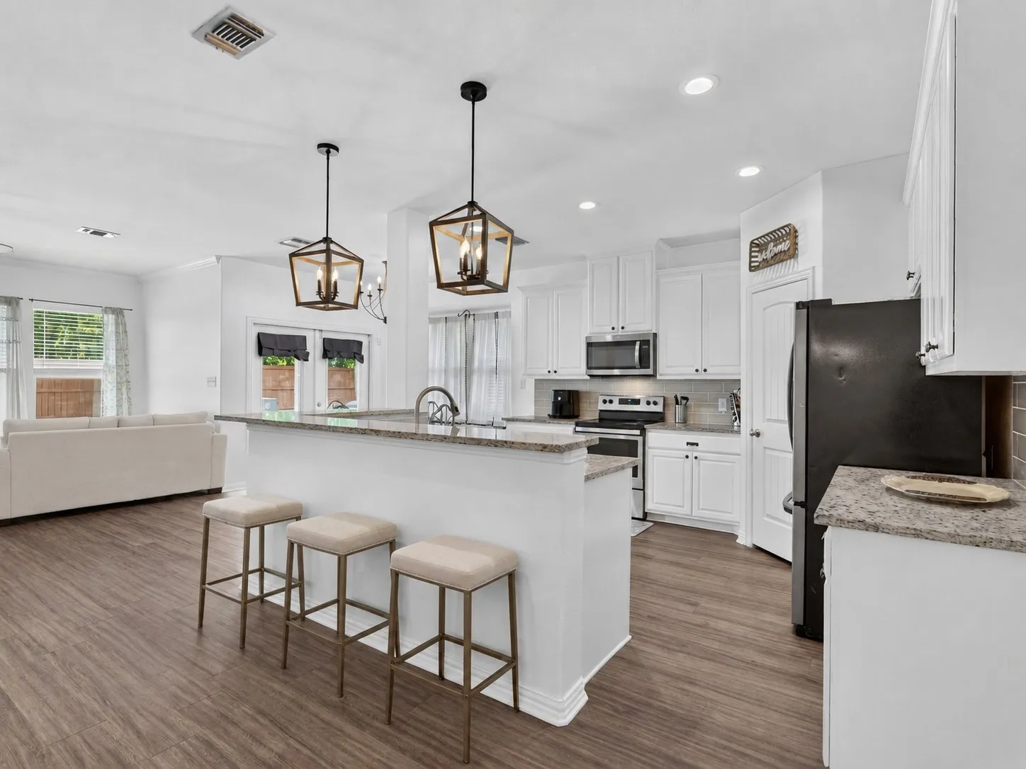 Kitchen with stainless steel appliances, granite countertops, and a spacious center island open to the living and dining areas. Virtually staged.