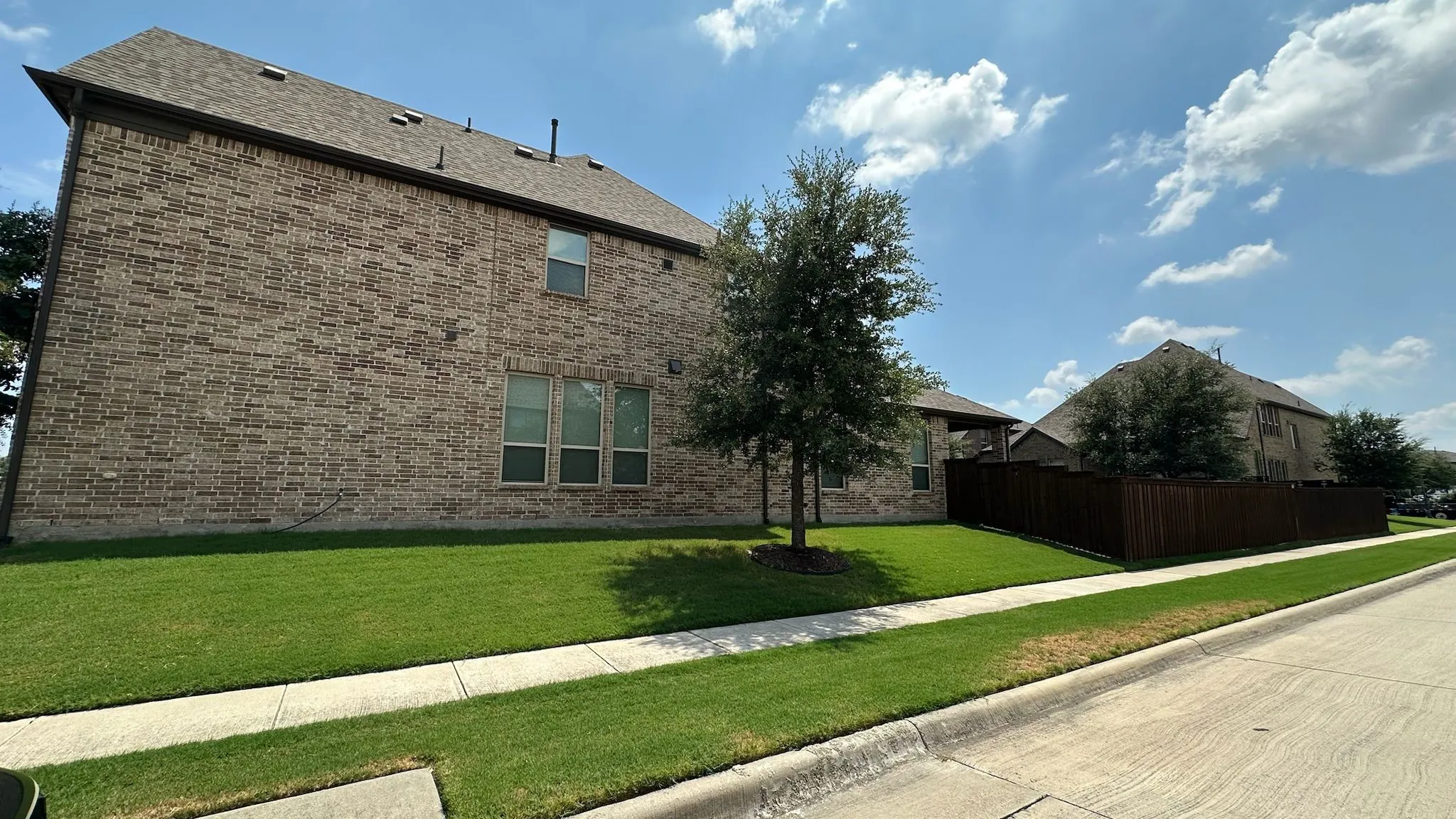 Brick exterior with multiple windows and a shingle roof