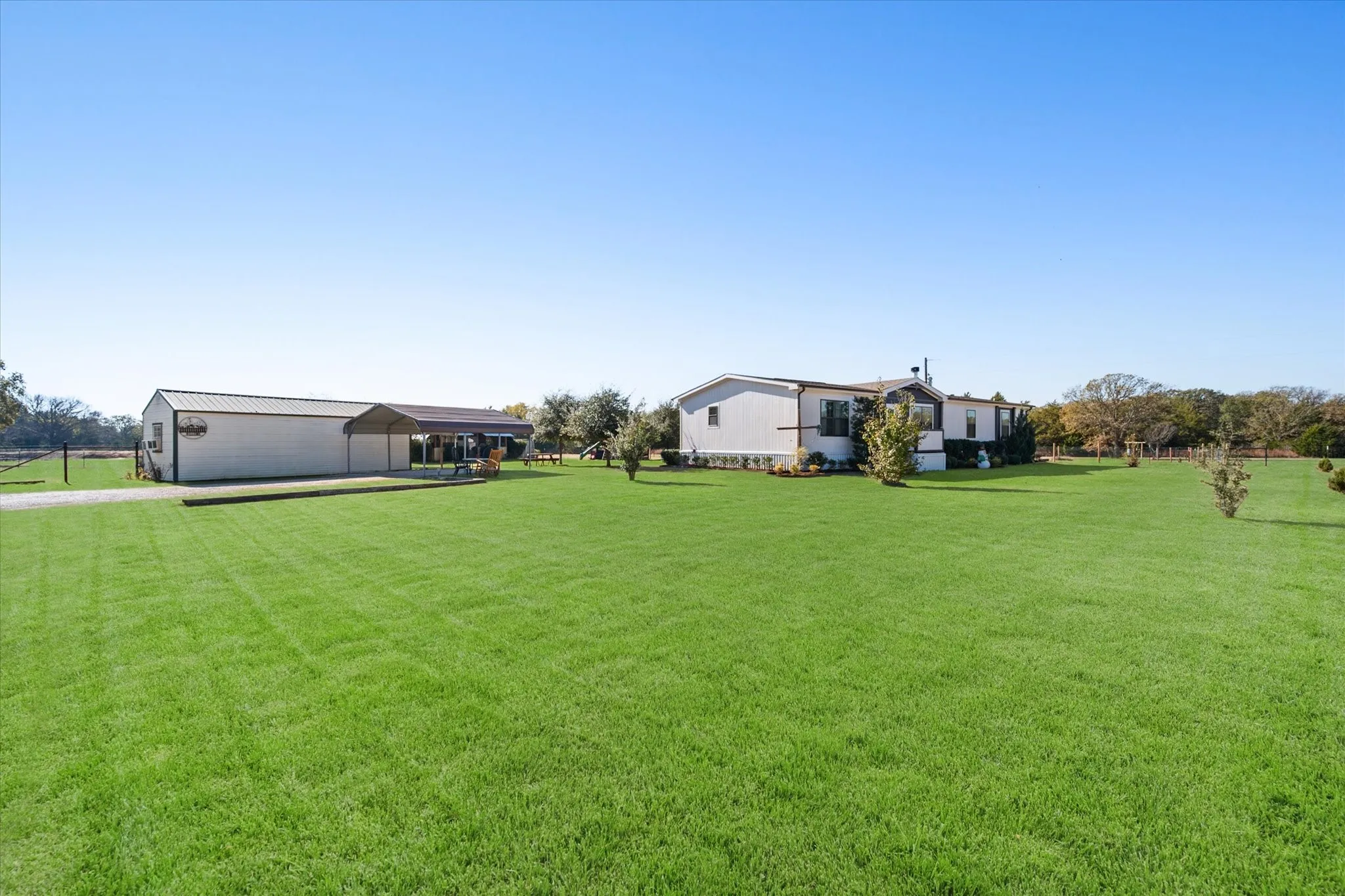 Expansive manicured lawn with mature landscaping and shade trees, offering substantial grounds ideal for outdoor recreation