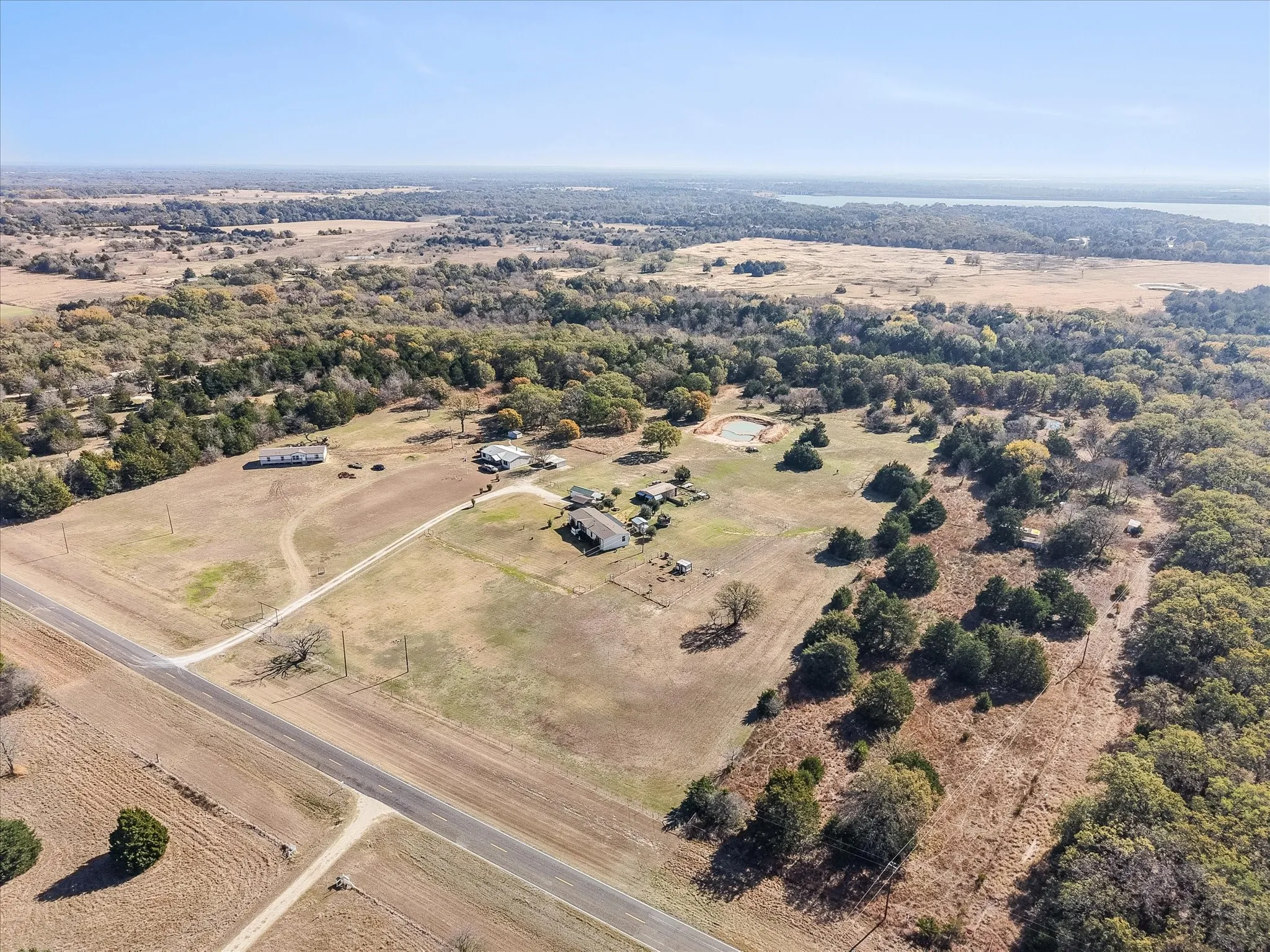 Expansive rural property featuring a lake and a main residence, additional structures, and a pond